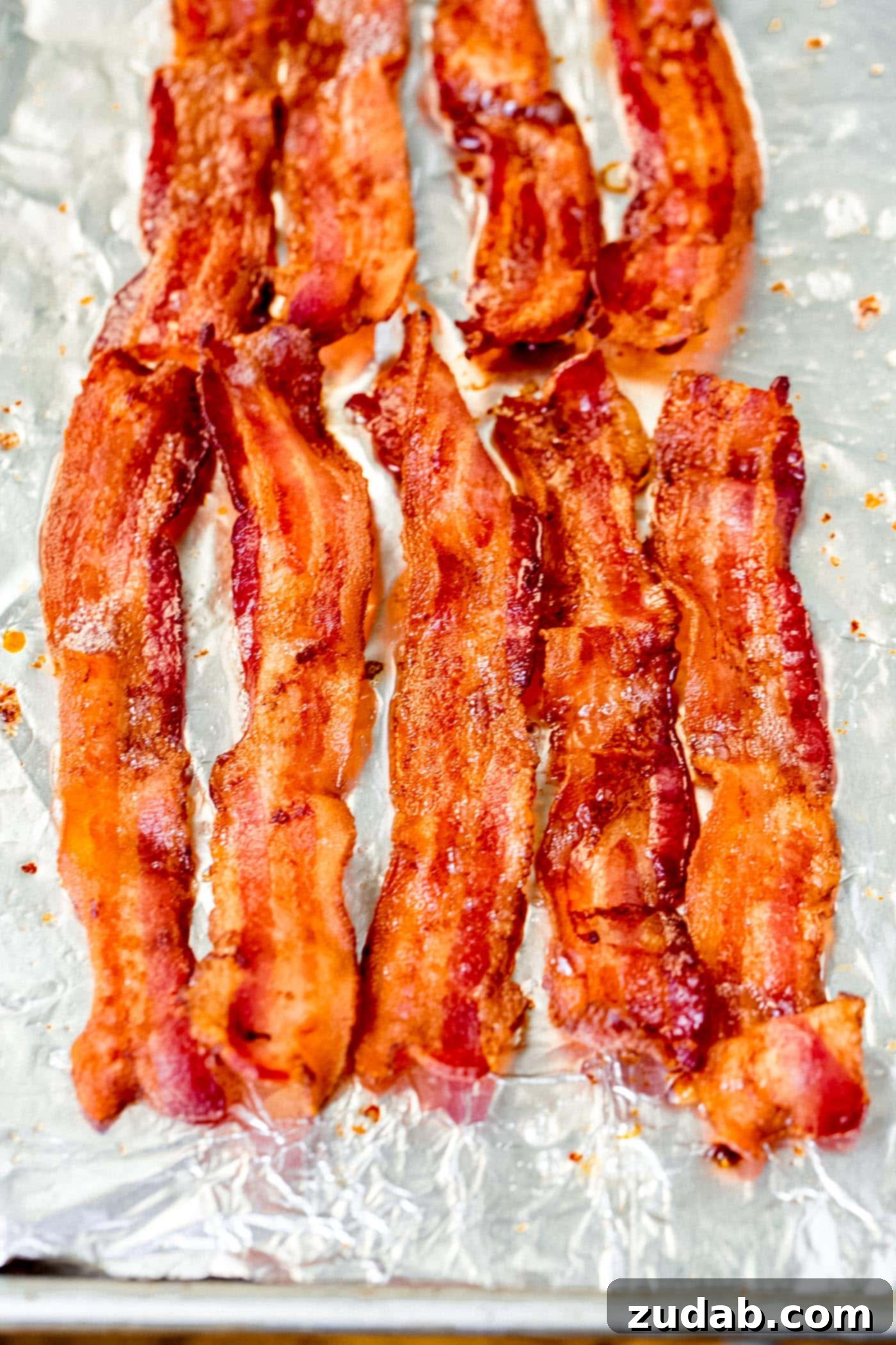 Mastering the Art of Perfect Bacon 4 Slices of perfectly crisp bacon on a baking sheet lined with foil.