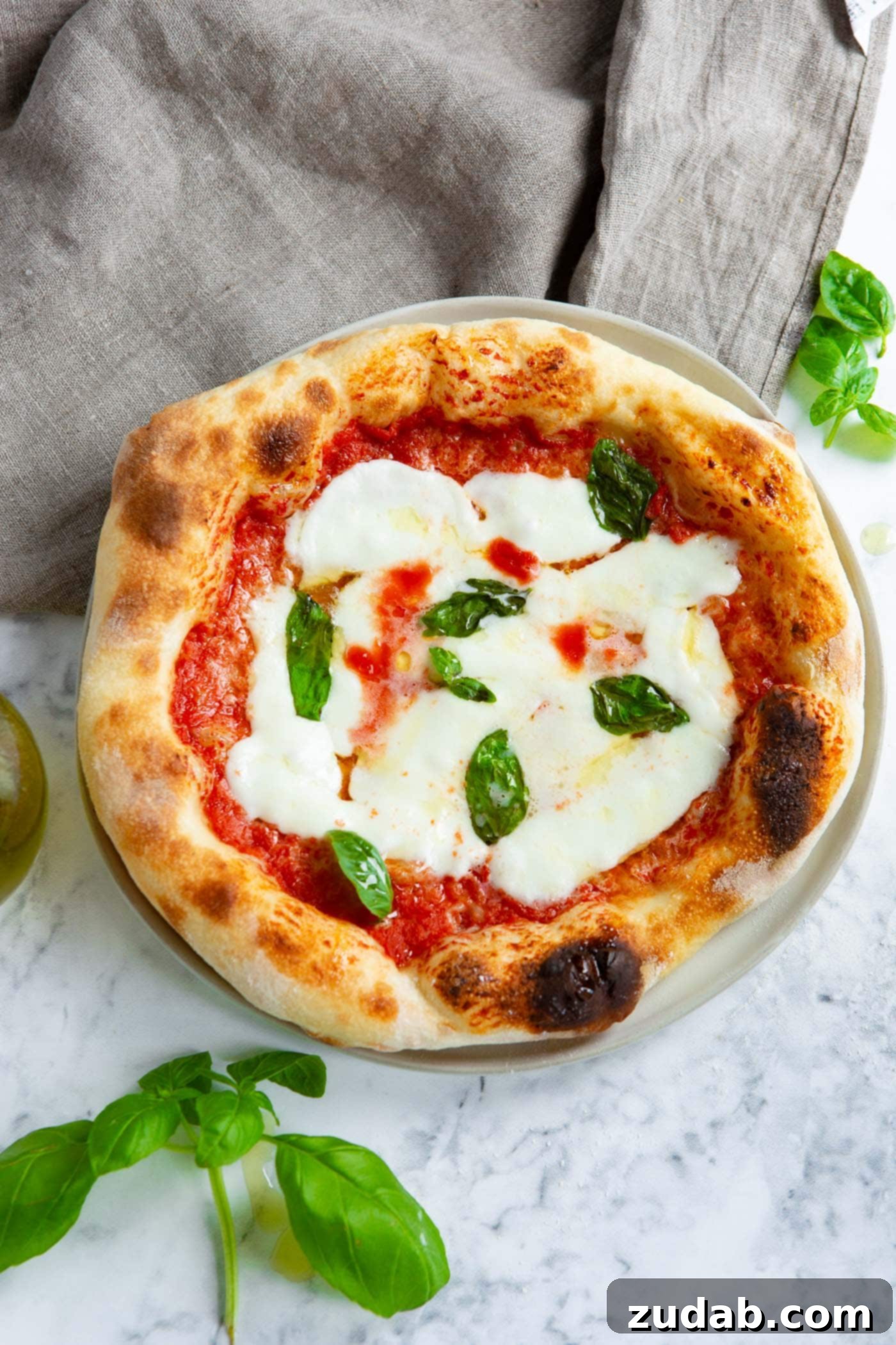 A freshly prepared homemade Margherita pizza, generously topped with vibrant green basil leaves, bubbling mozzarella, and a rich red sauce, embodies the ideal pizzeria-style pizza.
