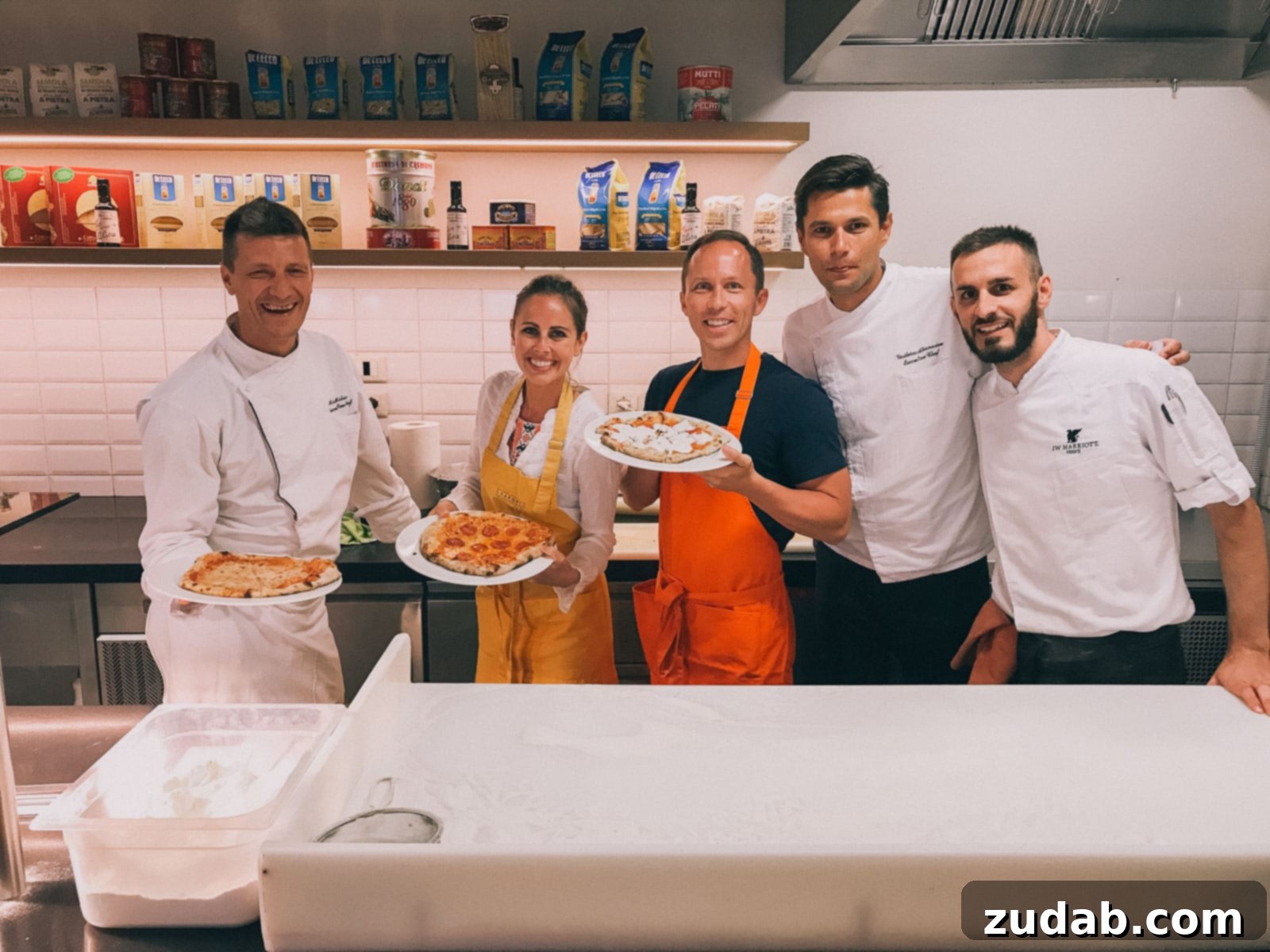 A chef demonstrates pizza-making techniques during a private cooking class at the JW Marriott in Venice, Italy, with attendees eagerly observing.
