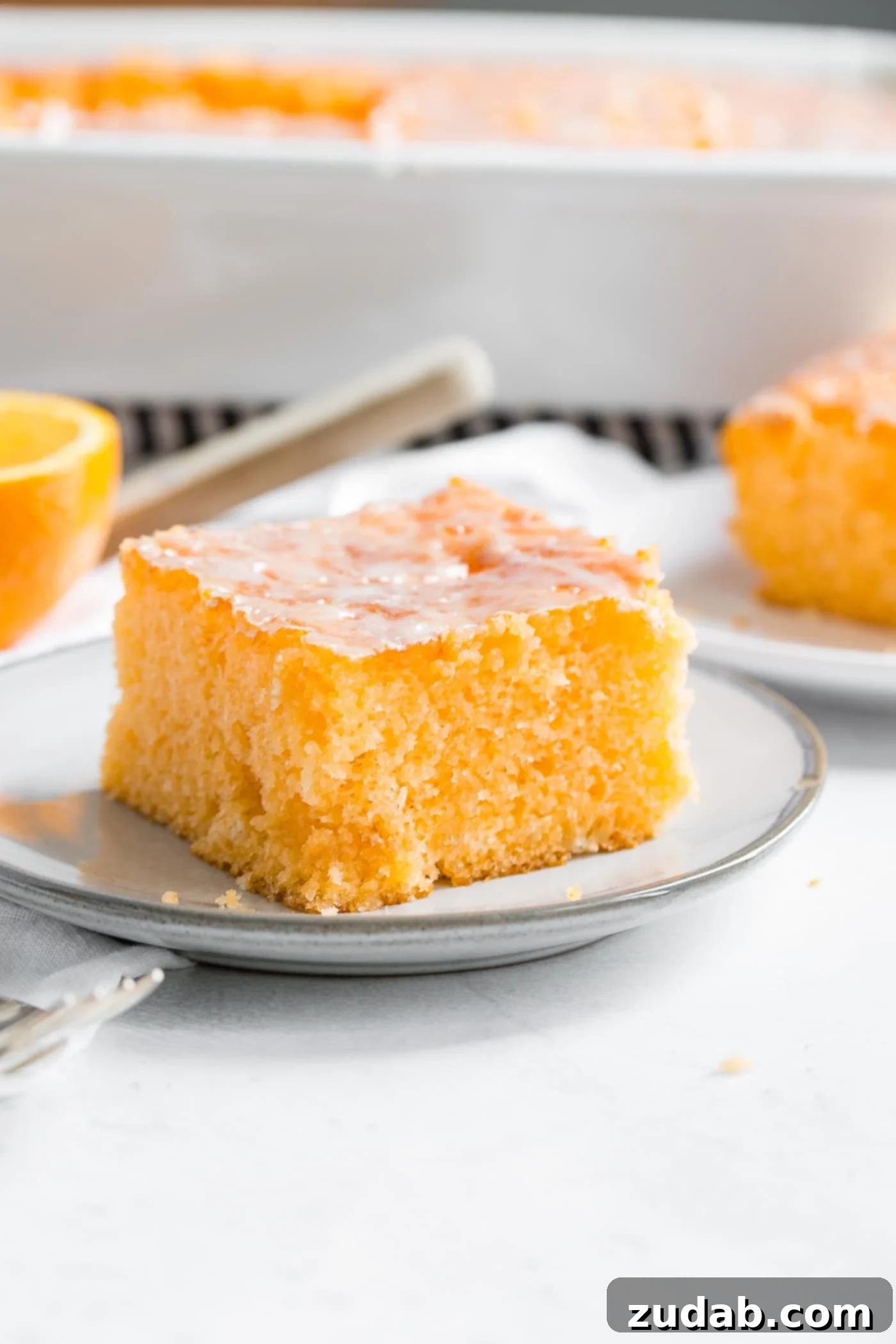 Delicious Orange Jello Cake Slice A beautifully presented slice of Orange Jello Cake on a small white plate, ready to be enjoyed.