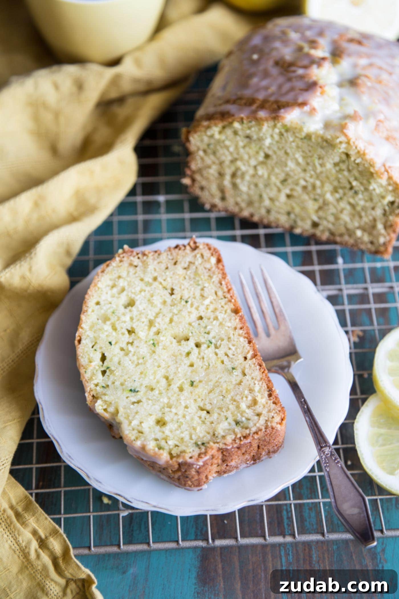 Zesty Lemon Zucchini Loaf 5 Close-up of a slice of Lemon Zucchini Bread on a wire rack, showing its fluffy texture.