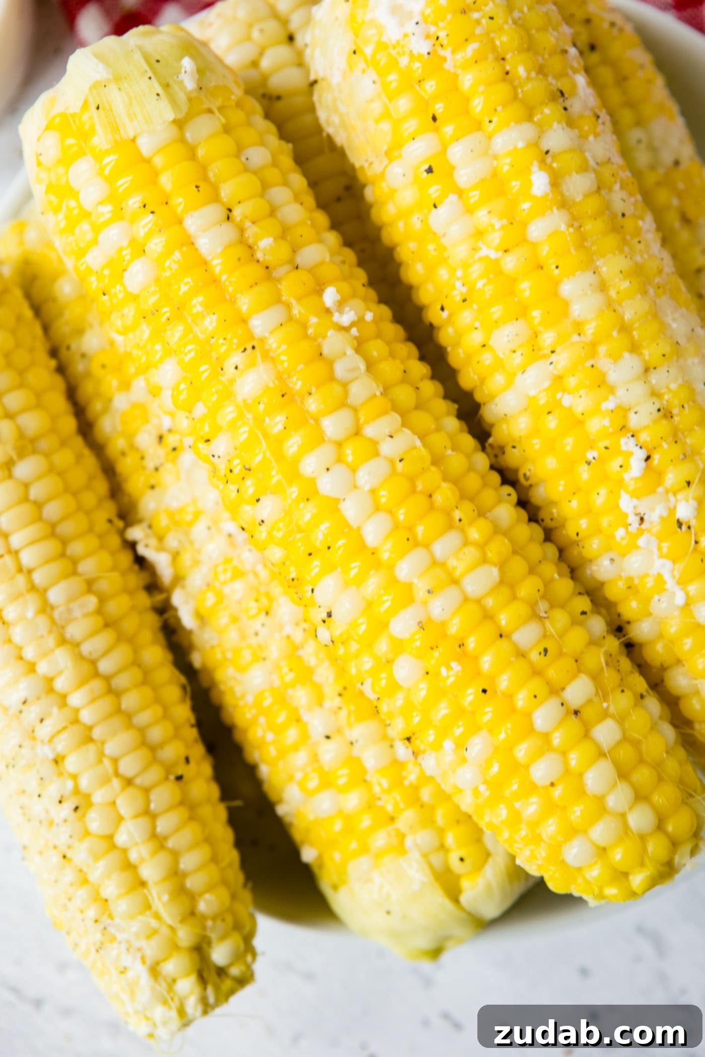 Easy Instant Pot Corn on the Cob 4 A close-up of four ears of cooked corn on the cob sprinkled with ground pepper.