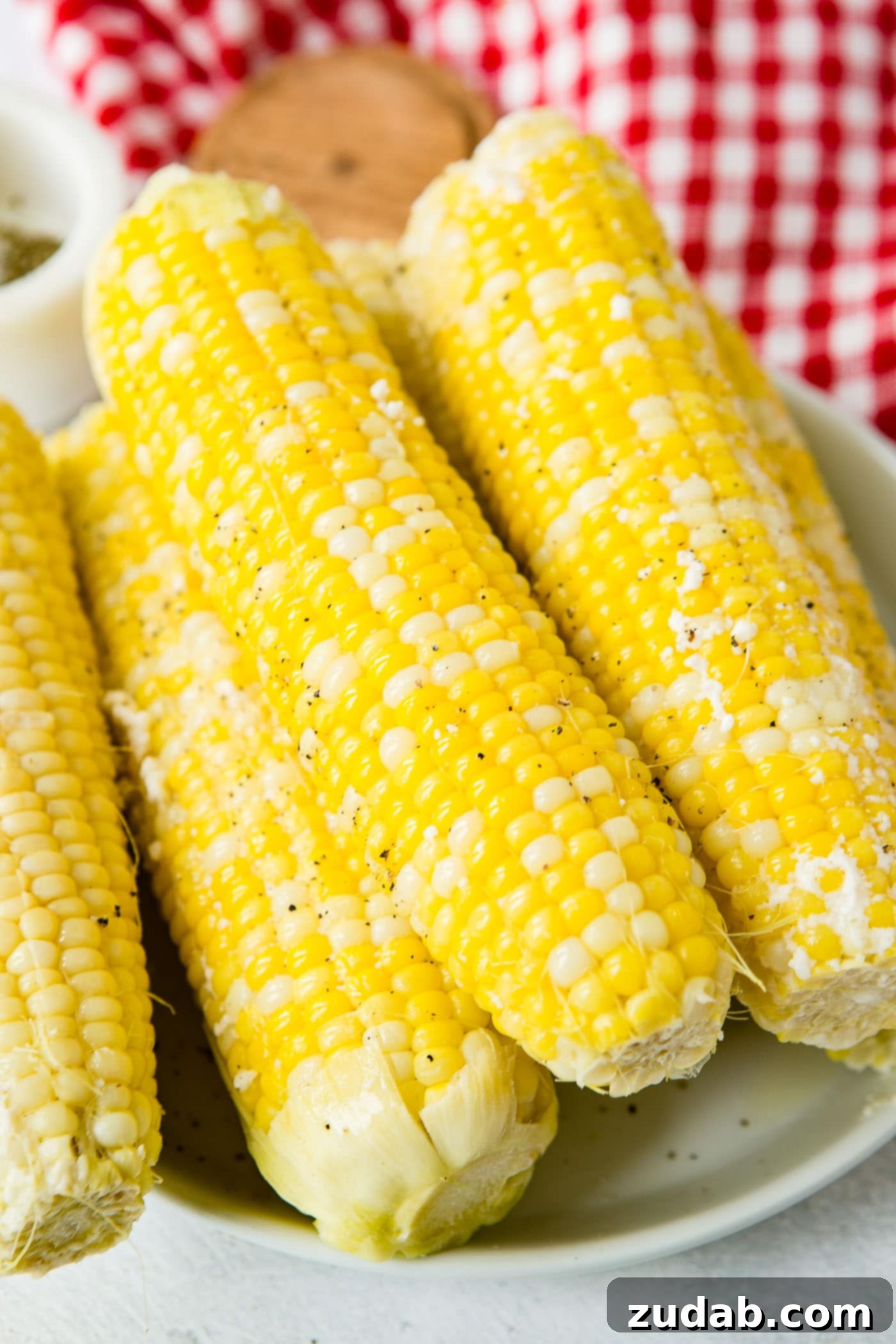 Easy Instant Pot Corn on the Cob 5 Four ears of cooked corn on the cob. The plate of corn is sitting on a red checked tea towel.