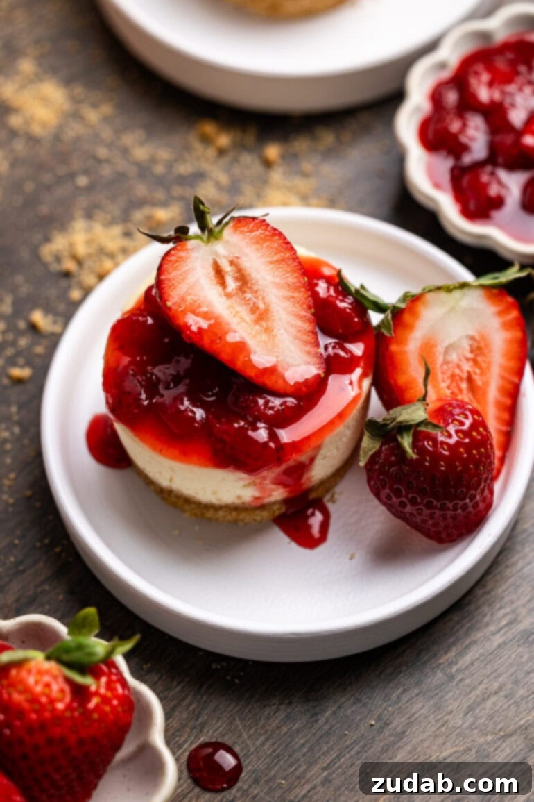 Luscious Strawberry Cheesecake Minis 6 An overhead shot of a mini strawberry cheesecake with strawberry topping. The cake is garnished with fresh slices of strawberries