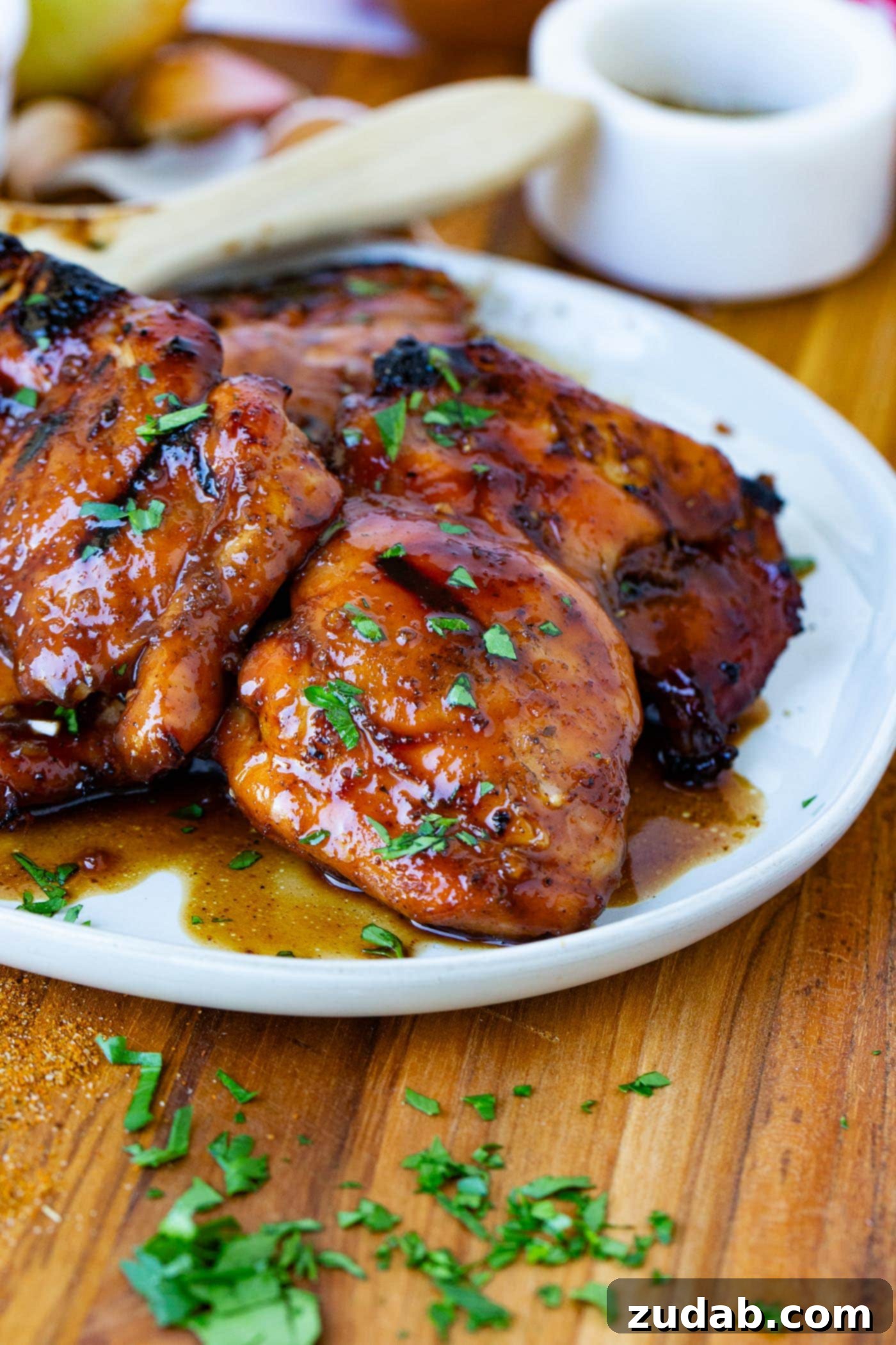 Marinated Smoked Chicken Thighs on the Traeger A serving plate of marinated smoked chicken thighs sprinkled with fresh green herbs.