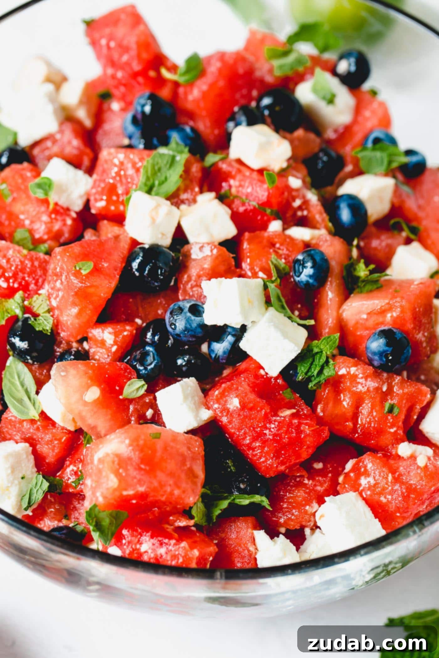 Blueberry Feta Watermelon Salad A close up of blueberry feta watermelon salad. There are bright read chunks of watermelon, blueberries, and cubes of feta cheese sprinkled with basil and mint leaves.