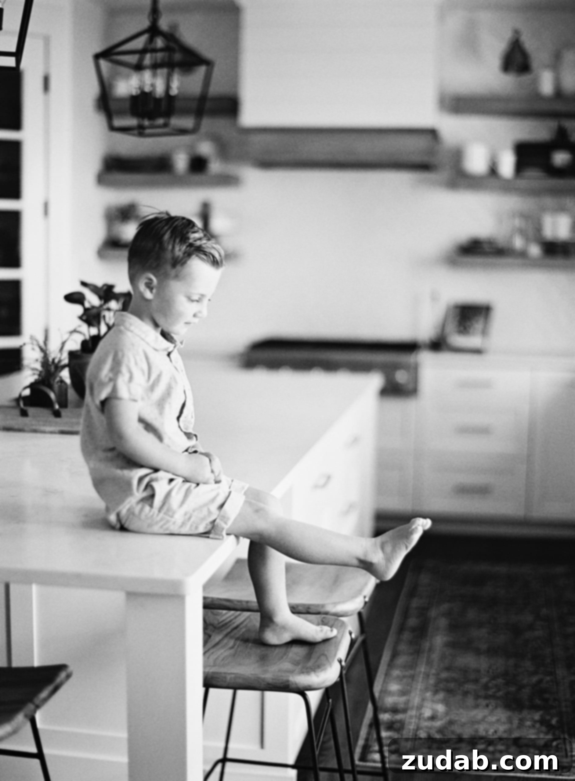Light Always Remains: Overcoming Childhood Fears A young boy sits on a kitchen counter, looking thoughtfully at his toes, embodying a moment of quiet reflection amidst fear of the dark.
