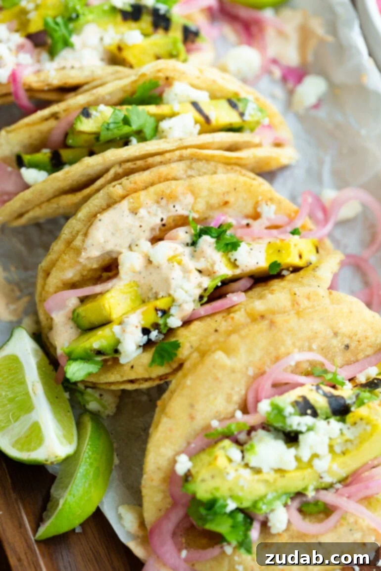 Smoky Grilled Avocado Tacos 2 a photo of grilled avocado tacos topped with pickled red onions, crumbled queso fresco and a lime crema.