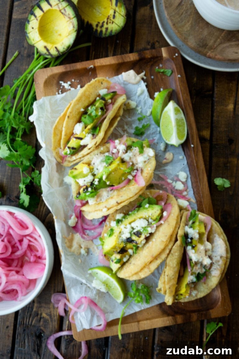 Smoky Grilled Avocado Tacos 7 a photo taken over a rectangular wooden serving tray topped with 5 grilled avocado tacos.