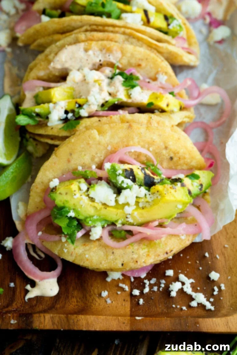 Smoky Grilled Avocado Tacos 10 a photo taken over the top of a taco filled with slices of grilled avocado, pickled red onions, crumbly queso fresco and a little salt and pepper.