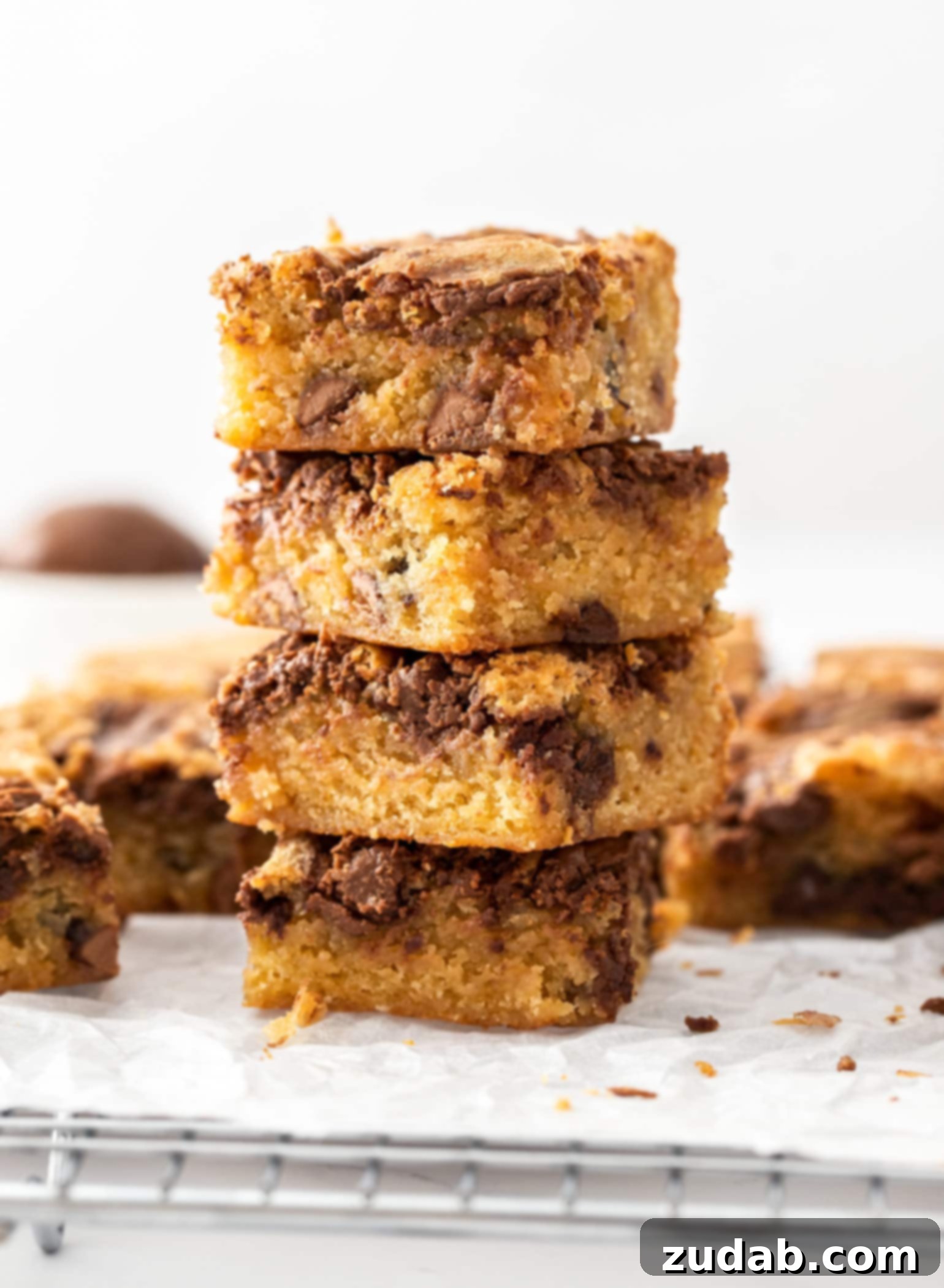 Decadent Nutella Blondies 2 A stack of 4 blondie bars sitting on a wire rack with more around them, highlighting their perfect golden-brown crust.