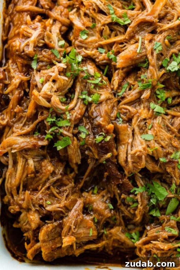 A large pan filled with perfectly shredded Cafe Rio Sweet Pork, garnished with fresh chopped cilantro, ready to be served in your favorite Mexican dishes.