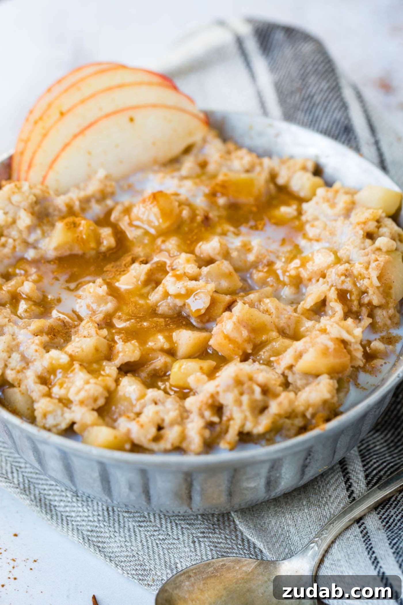 Apple Pie Slow Cooker Oatmeal A photo of apple pie slow cooker oatmeal topped with caramel and thinly sliced apples.