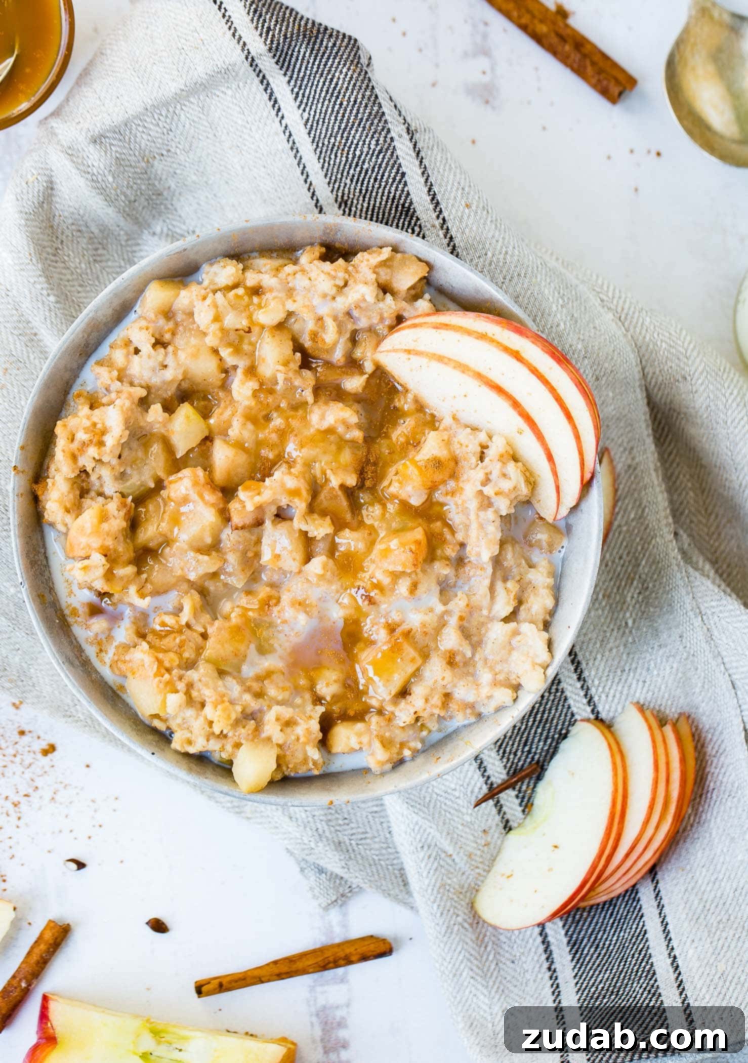 Apple Pie Slow Cooker Oatmeal A photo of a bowl of apple pie slow cooker oatmeal with caramel and thinly sliced apples on top with milk added