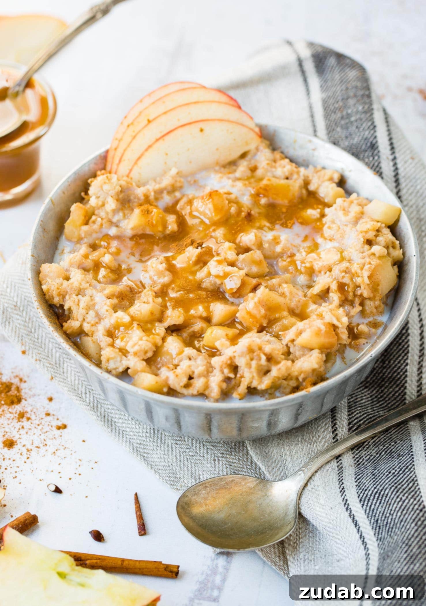 Apple Pie Slow Cooker Oatmeal A photo of a bowl of oatmeal full of apple chunks and topped with caramel drizzle and thinly sliced apples