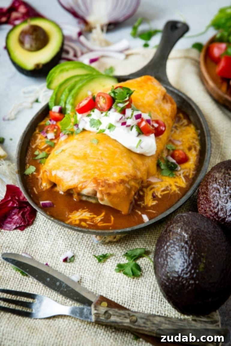 Weeknight Enchilada Beef Burritos 3 A generously sized ground beef burrito, completely enveloped in vibrant red enchilada sauce and a thick layer of melted, bubbly cheese, served directly from the cast iron pan for maximum flavor and warmth.