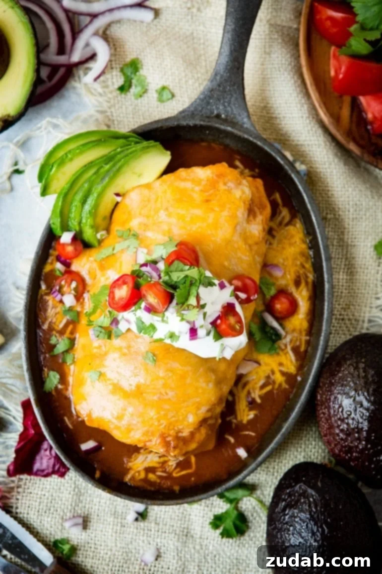 Weeknight Enchilada Beef Burritos 5 A close-up of a giant ground beef burrito, baked to perfection in a cast iron skillet, showcasing its rich red enchilada sauce and a blanket of bubbling, golden melted cheese, with perfectly crisped edges and a savory, melty center.