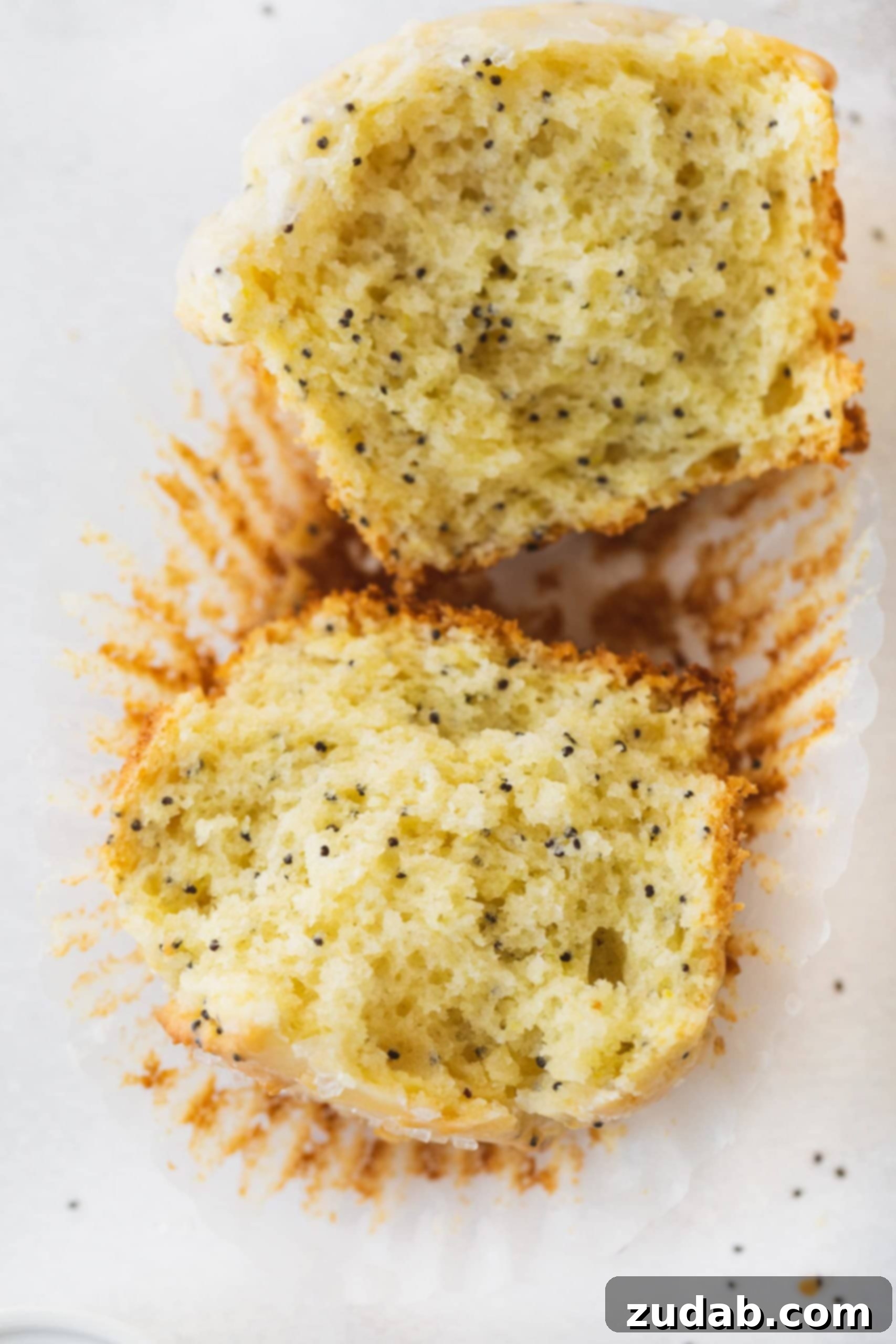 Lemon Poppy Seed Muffins A lemon poppy seed muffin that is broken in half. You can see the poppy seeds in the muffin.
