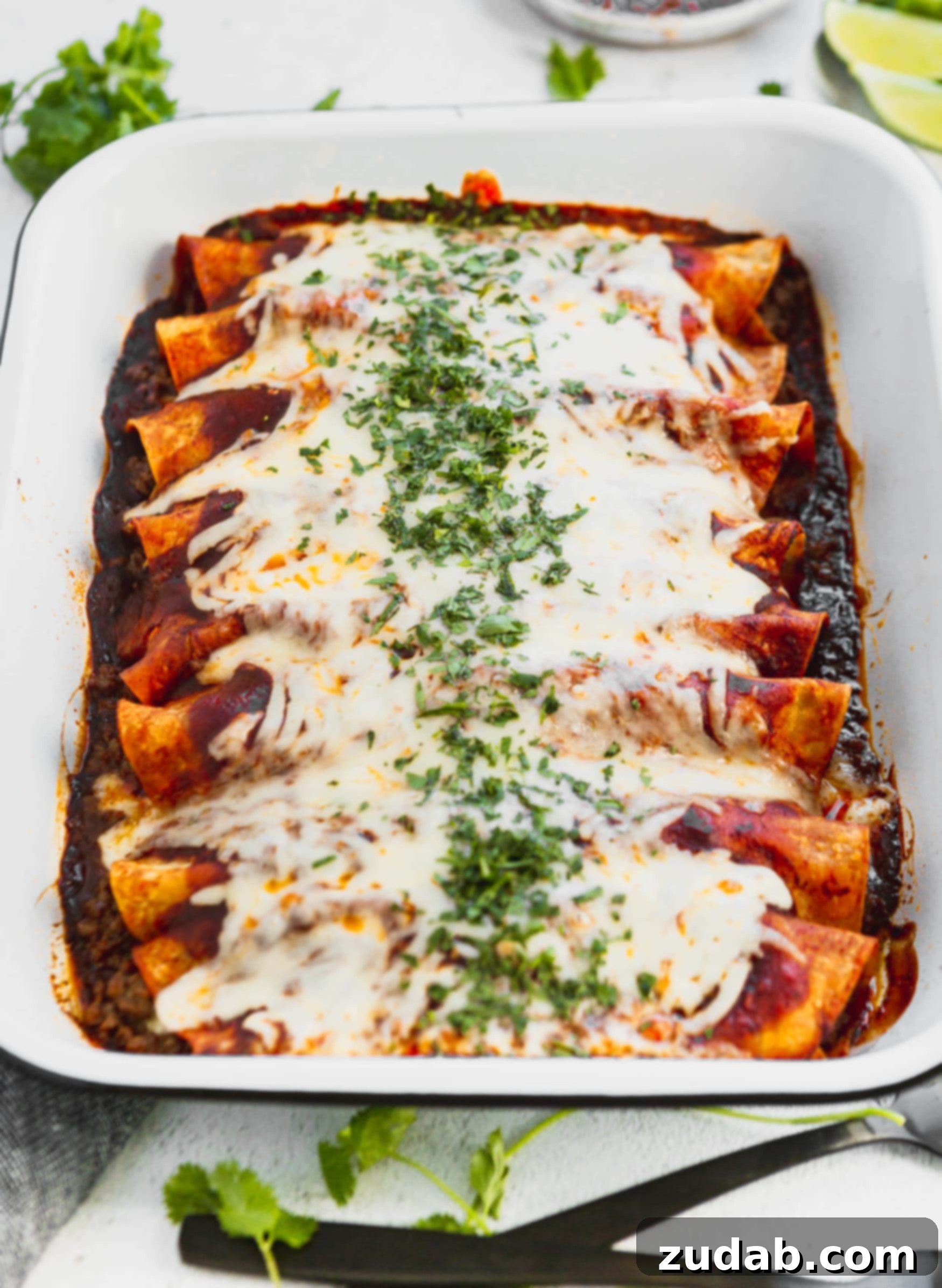 Family Favorite Cheesy Ground Beef Enchiladas A photo of a pan of ground beef enchiladas covered in melted cheese and finely chopped cilantro.