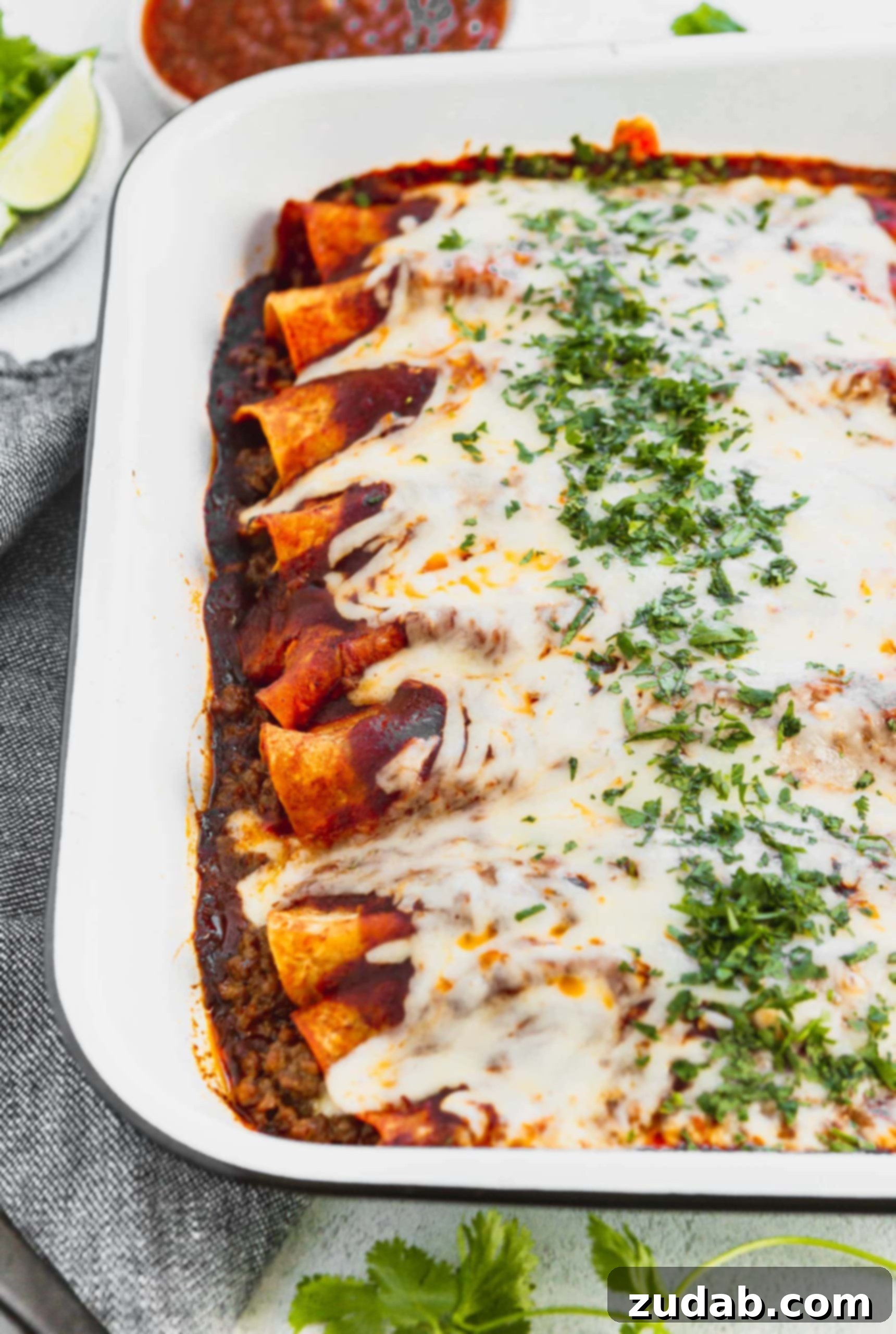 Family Favorite Cheesy Ground Beef Enchiladas A photo of a pan of beef enchiladas covered in melted cheese and finely chopped cilantro.