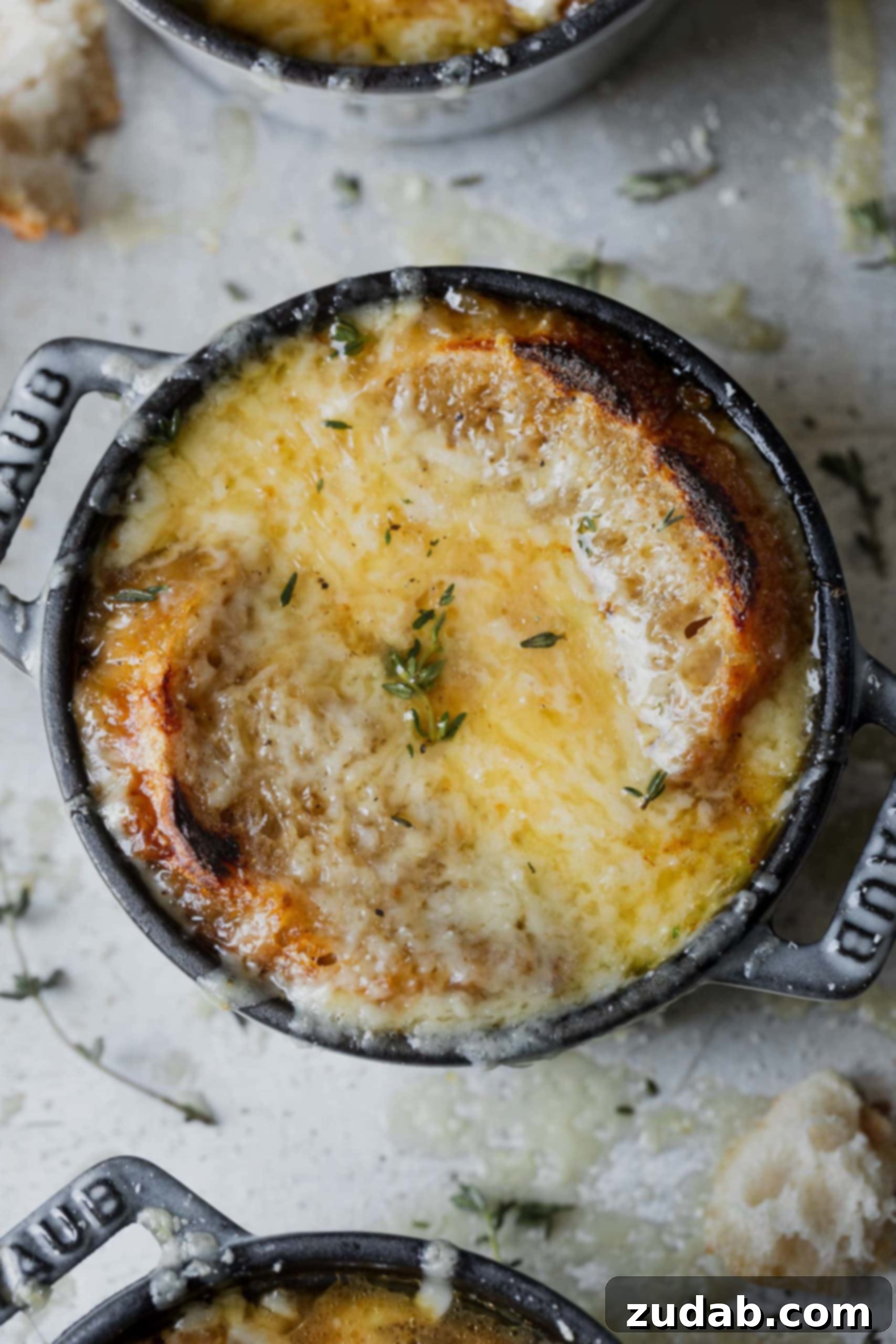 Better Than Steakhouse Onion Soup A close-up shot of a single bowl of French onion soup with beautifully melted, bubbly cheese and a toasted baguette slice on top, ready to be enjoyed.