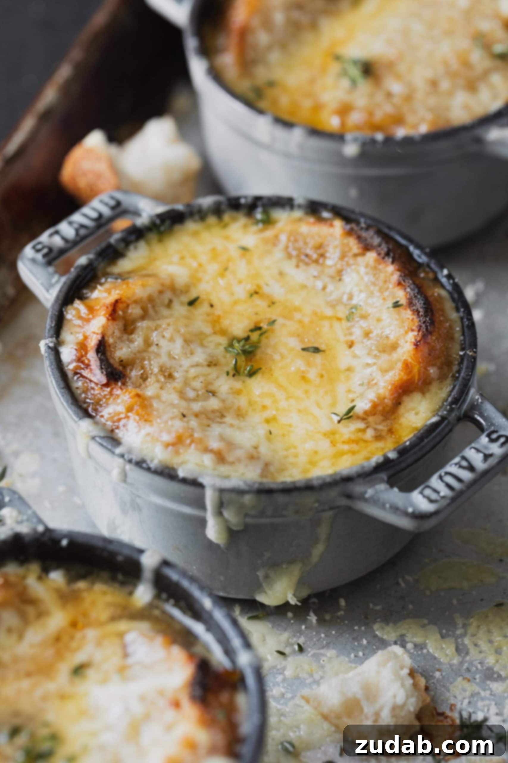 Better Than Steakhouse Onion Soup A baking sheet with multiple bowls of French onion soup, each adorned with a perfect melted cheese and toasted bread topping, ready for serving.