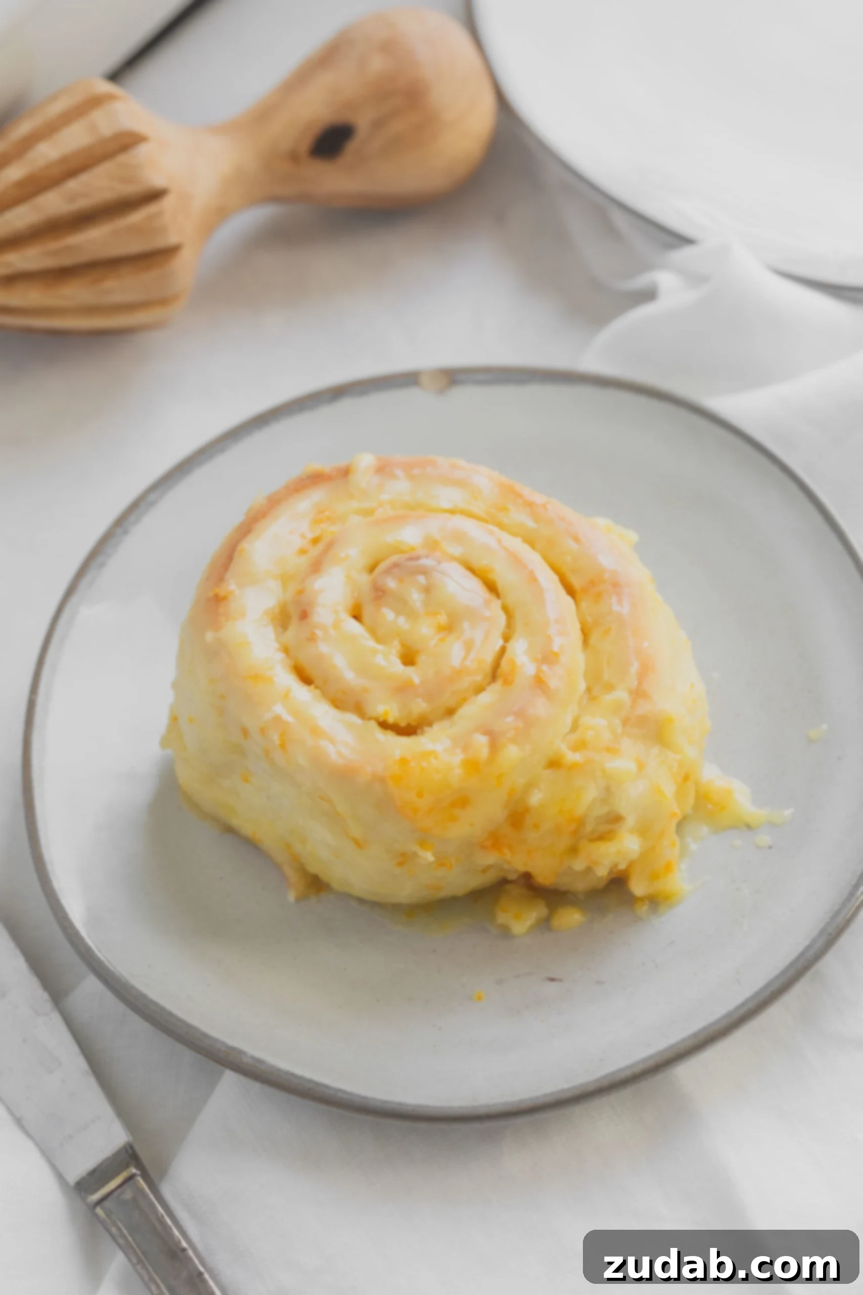Orange Rolls An orange roll on a white dessert plate. The roll is frosted with an orange glaze.