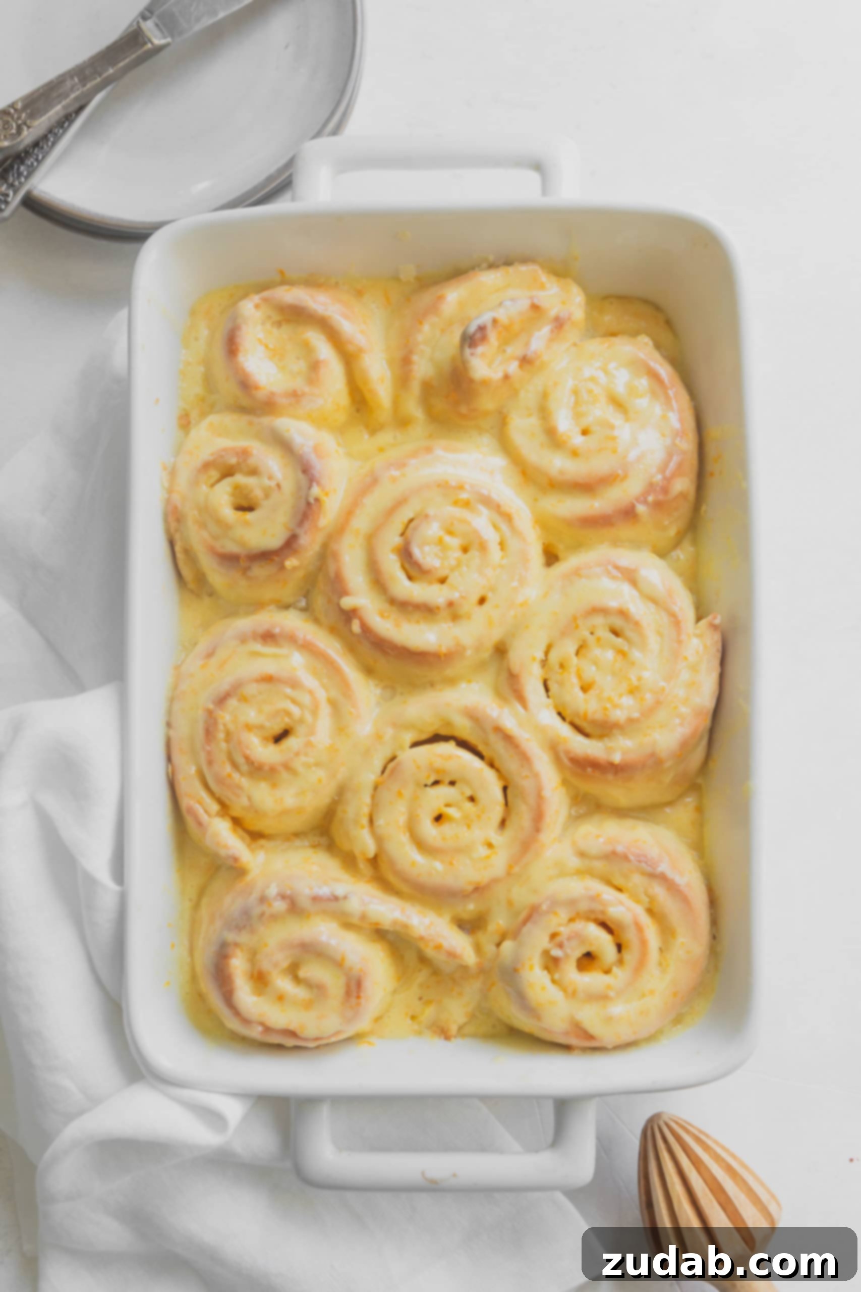 Orange Rolls A baking pan filled with orange rolls ready to be baked. They are rolled like a cinnamon roll and have bits of orange zest.