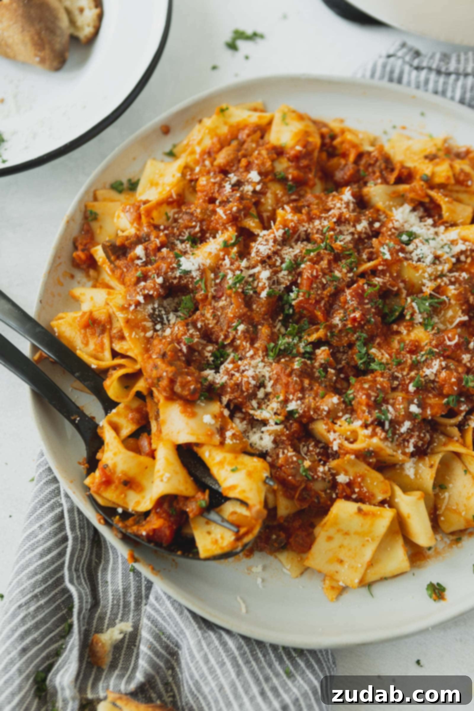 Rich & Flavorful Vegan Bolognese Sauce A serving of pasta with a rich and bright vegan bolognese sauce, artfully topped with grated cheese (optional, for non-vegans) and fresh cilantro.