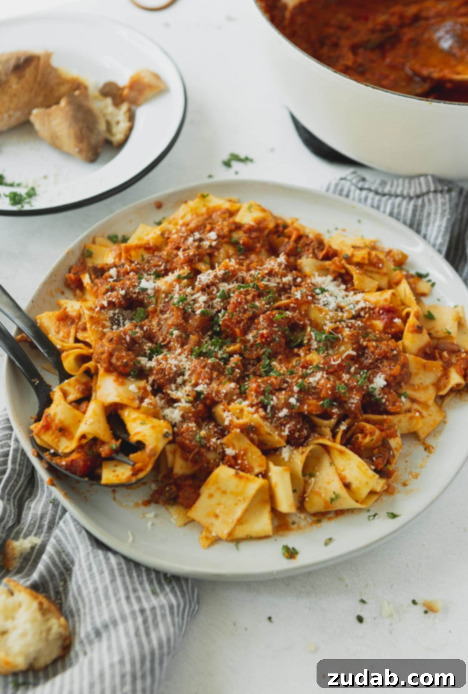 Vegan Bolognese Pasta Meal A plate brimming with pasta and vegan bolognese sauce, garnished with grated cheese (optional) and cilantro, with a fork poised for a delicious meal.
