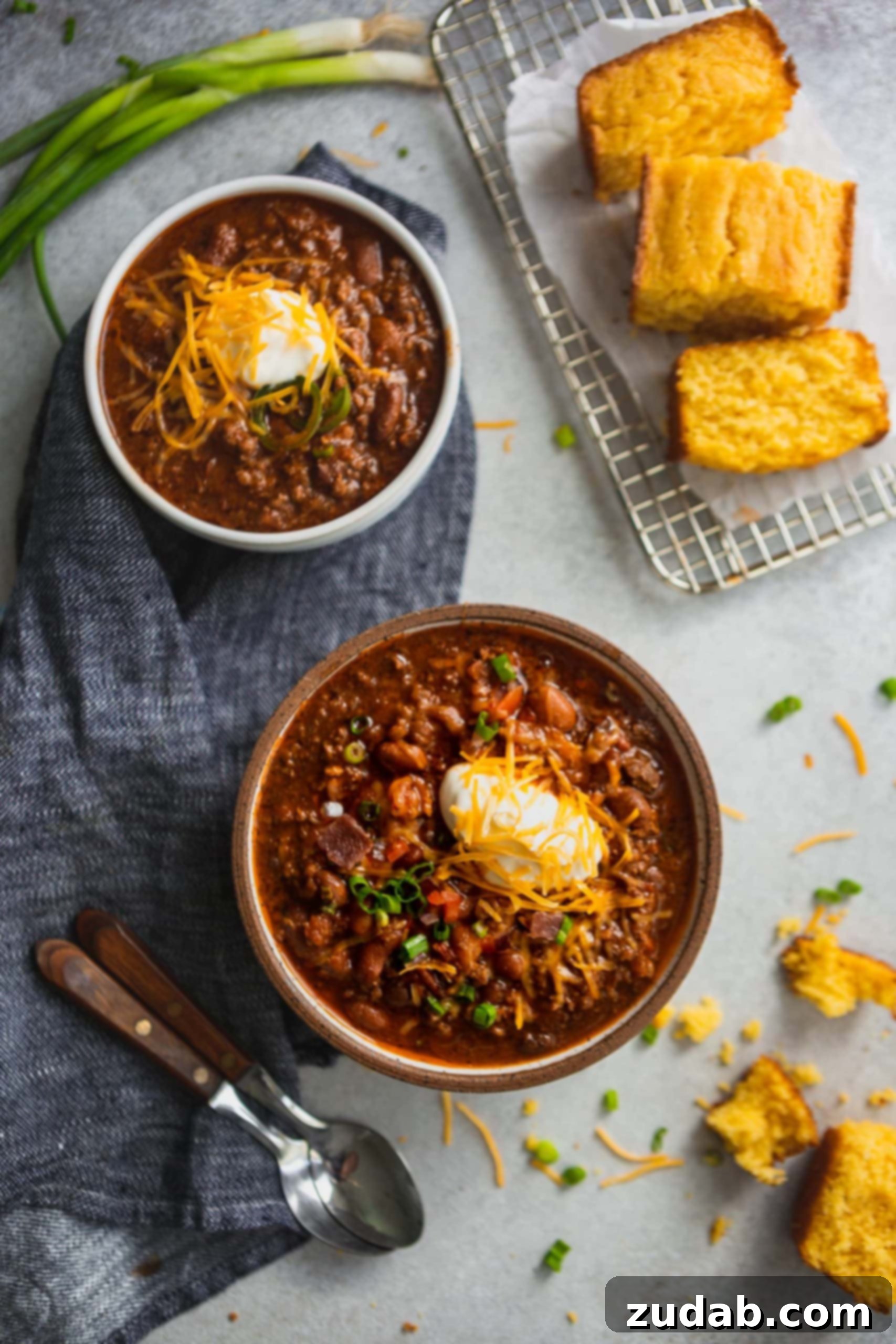 The Ultimate Chili Recipe 2 Two bowls of the best chili. The chili is made with beans, ground beef and herbs and spices. It is topped with sour cream and grated cheese.