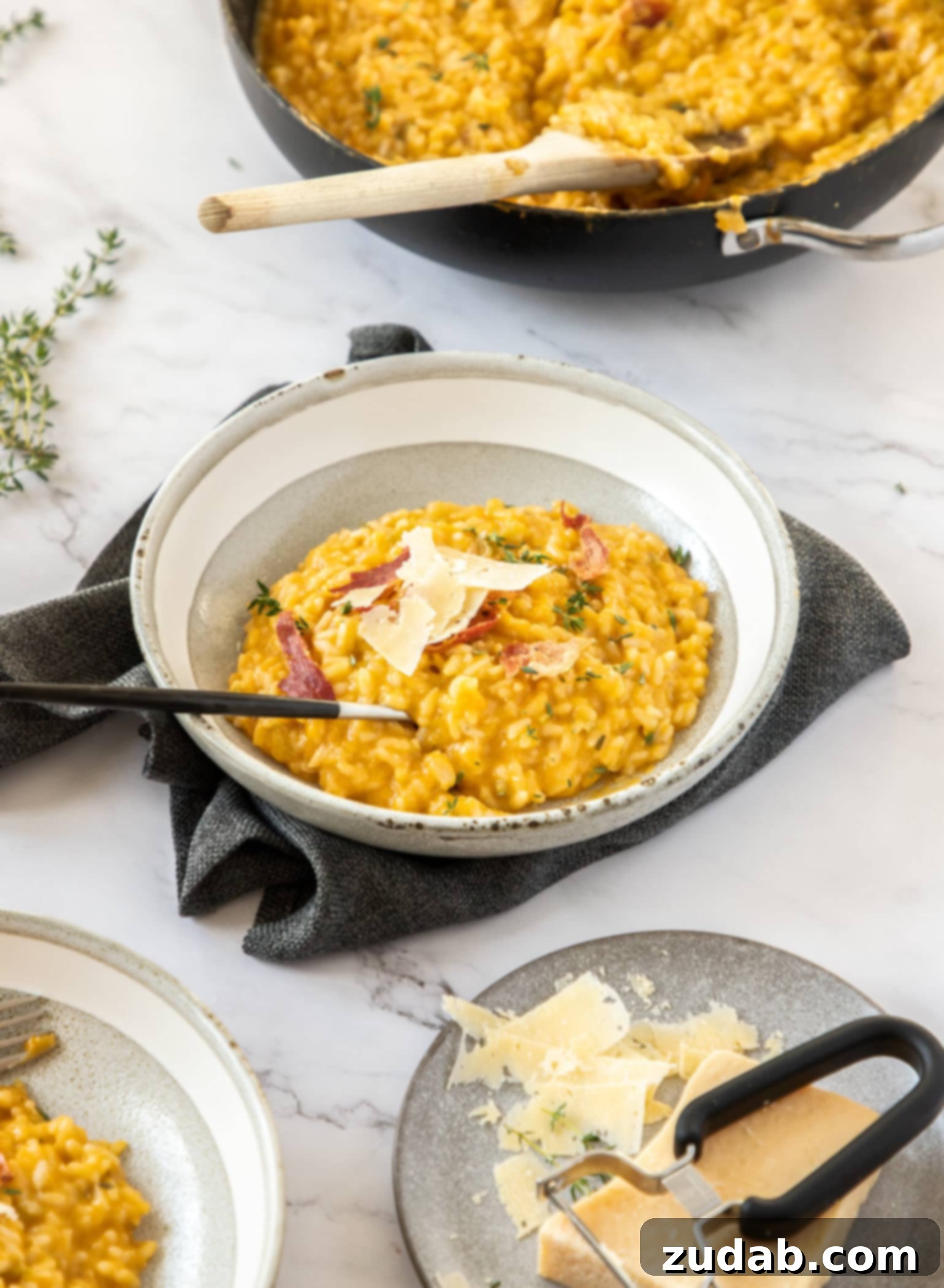 A grey bowl on a dark grey napkin. It's filled with orange coloured risotto