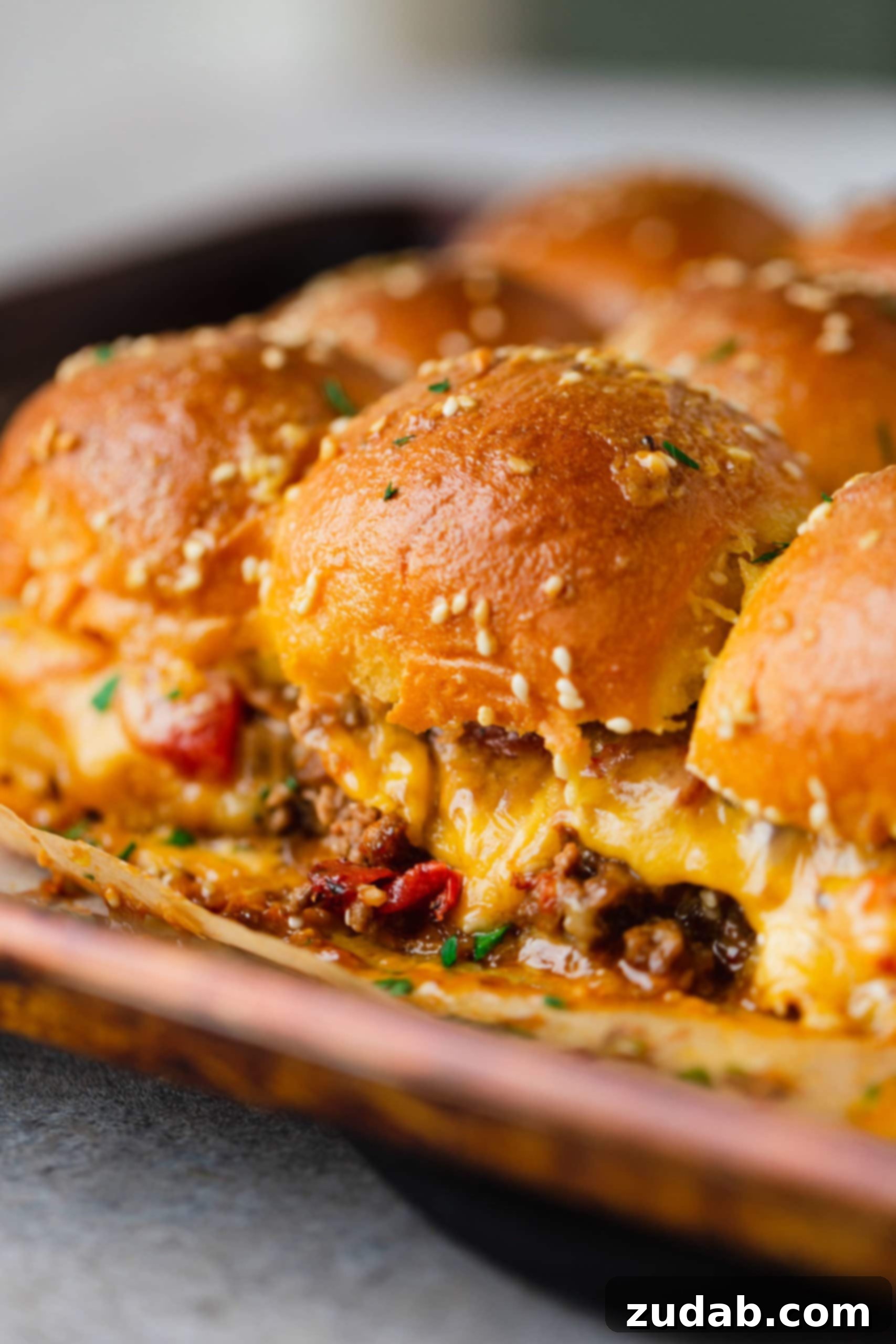 A plate of cheeseburger sliders. The cheese is oozing out from the buns.