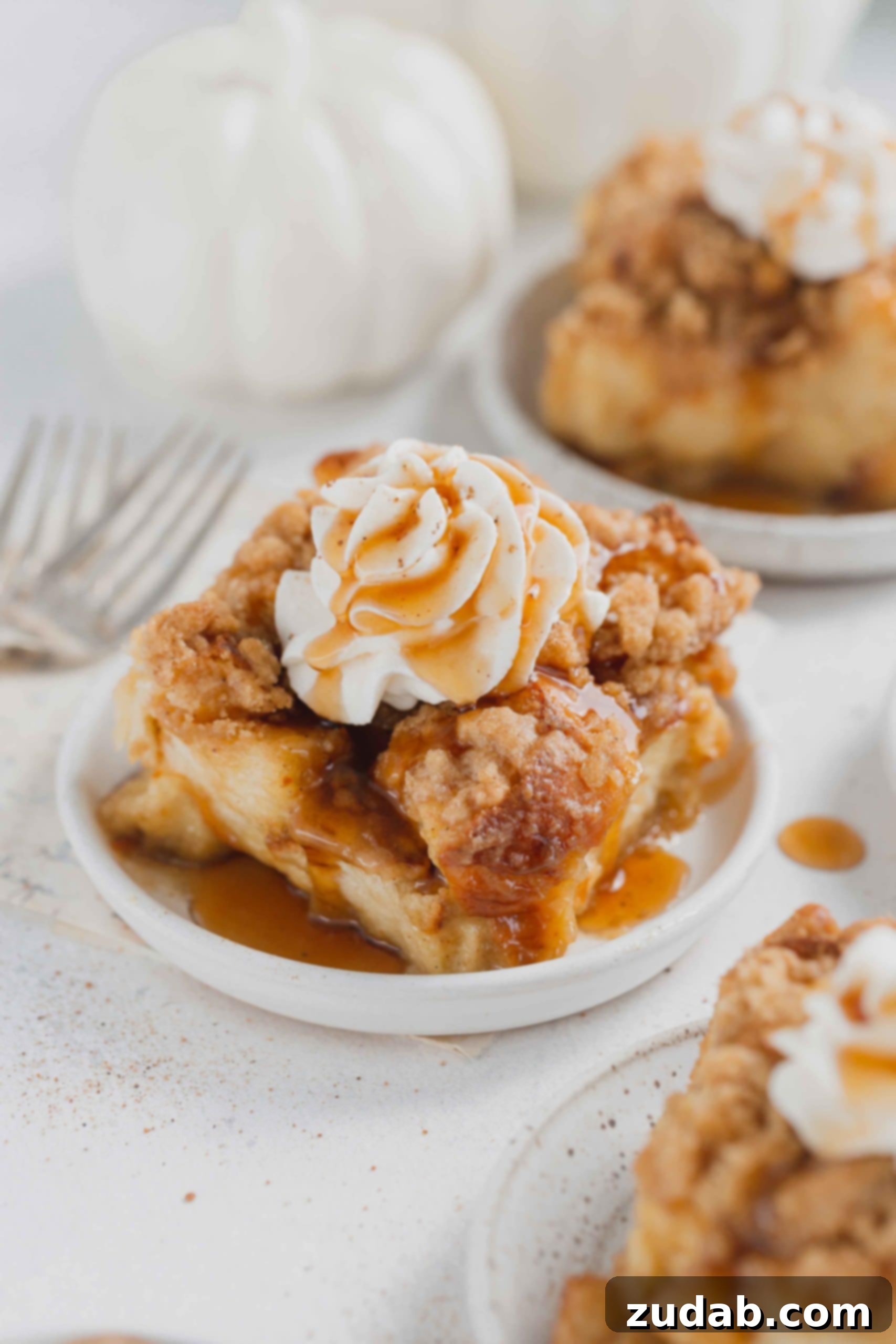 Eggnog French Toast Casserole Eggnog french toast casserole on a serving plate. The french toast is topped with whipped cream and a little syrup.