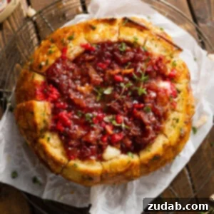 The Ultimate Tear and Share Baked Brie 2 A freshly baked sourdough bread bowl filled with melted baked brie and raspberry bacon onion jam, ready to be served as an appetizer.