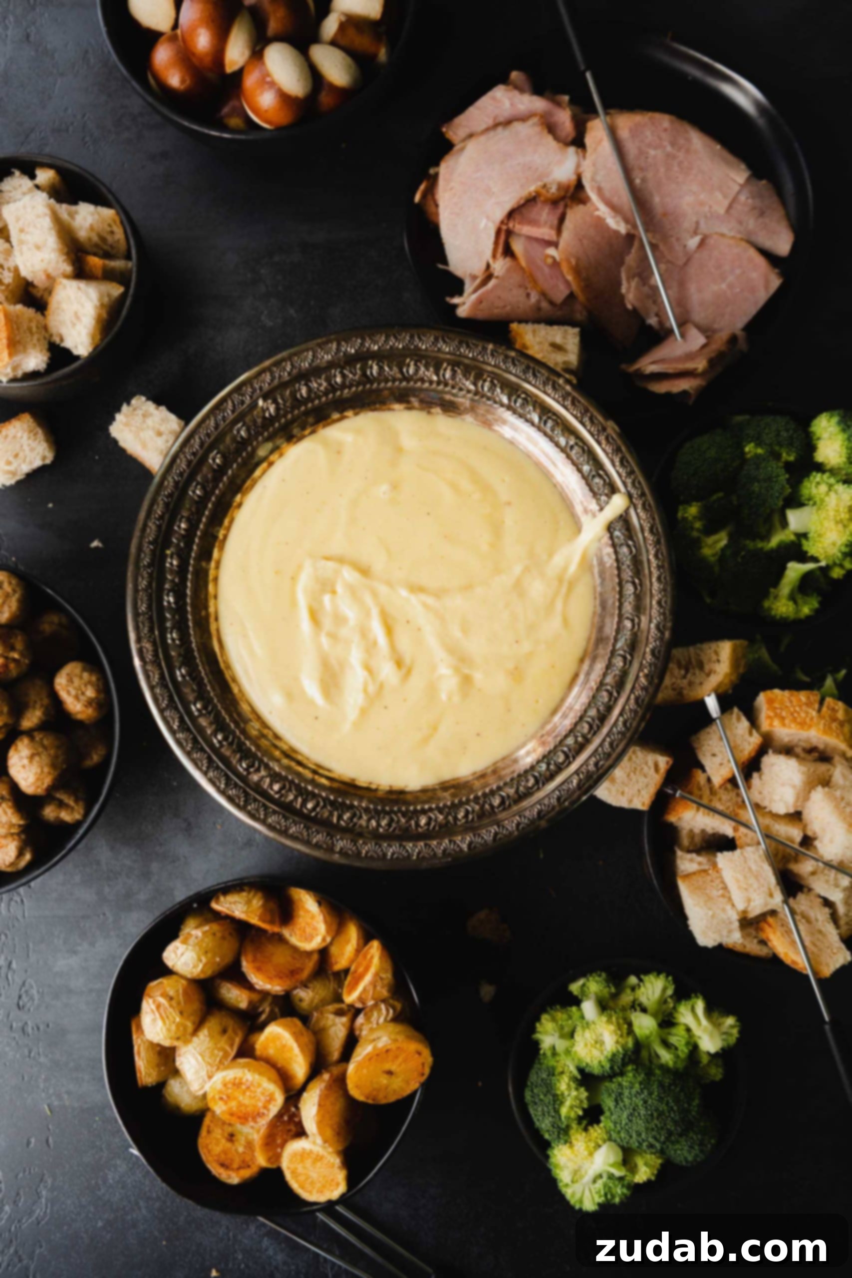Perfect Cheese Fondue and What to Dip in Fondue A bowl of cheese fondue. It is smooth and cheesy and there are vegetables and bread around it for dipping.