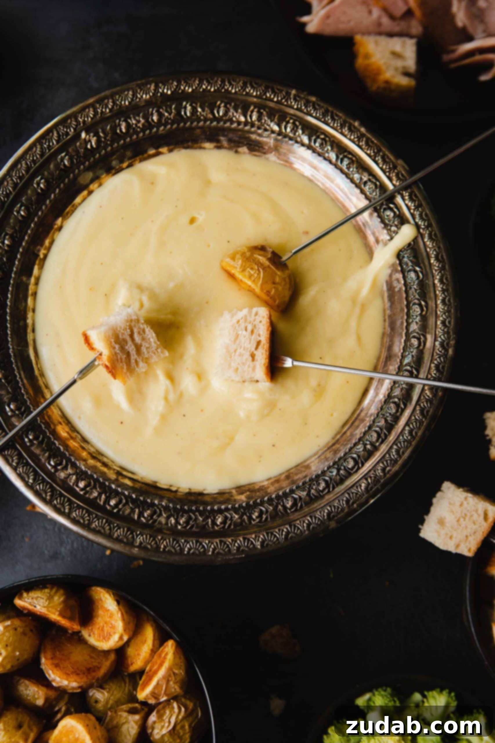 Perfect Cheese Fondue and What to Dip in Fondue A bowl of smooth cheese fondue with skewers of bread being dipped in.