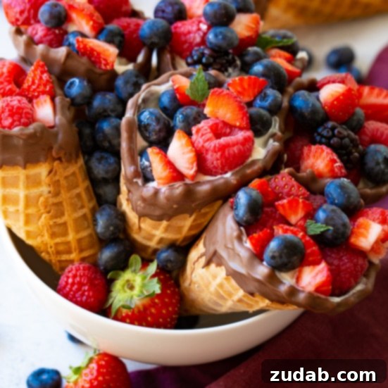 Over 25 Healthy Recipes 22 Colorful waffle cone fruit and yogurt cups filled with creamy yogurt and assorted fresh fruits, displayed on a wooden board.
