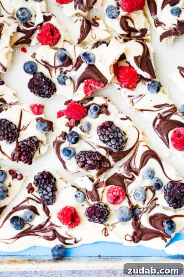 Over 25 Healthy Recipes 24 A tray of frozen healthy chocolate swirled berry yogurt bark, broken into pieces, showcasing vibrant colors and enticing swirls.