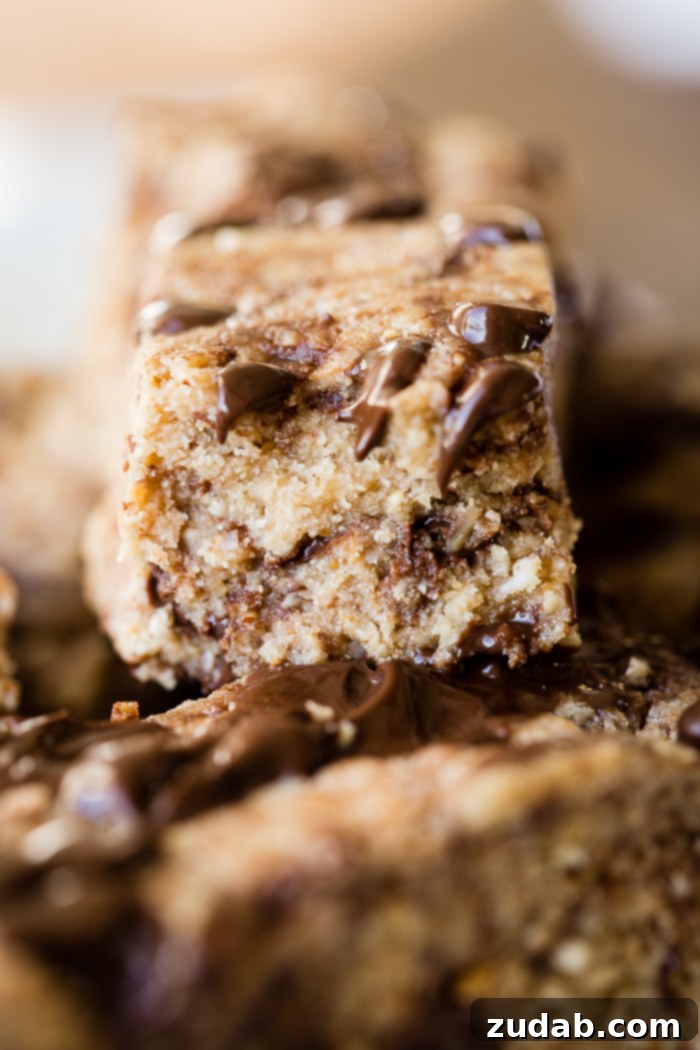 Over 25 Healthy Recipes 26 Several homemade chocolate chip cookie dough protein bars, soft and chewy, with visible chocolate chips, on a rustic surface.