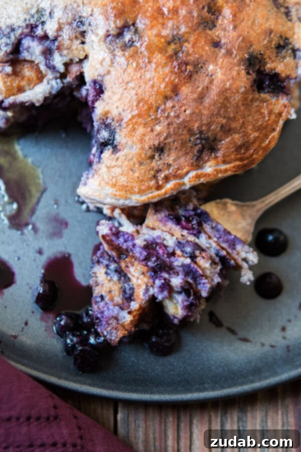 Over 25 Healthy Recipes 6 A stack of golden-brown wild blueberry cottage cheese pancakes, generously topped with fresh blueberries, on a white plate.
