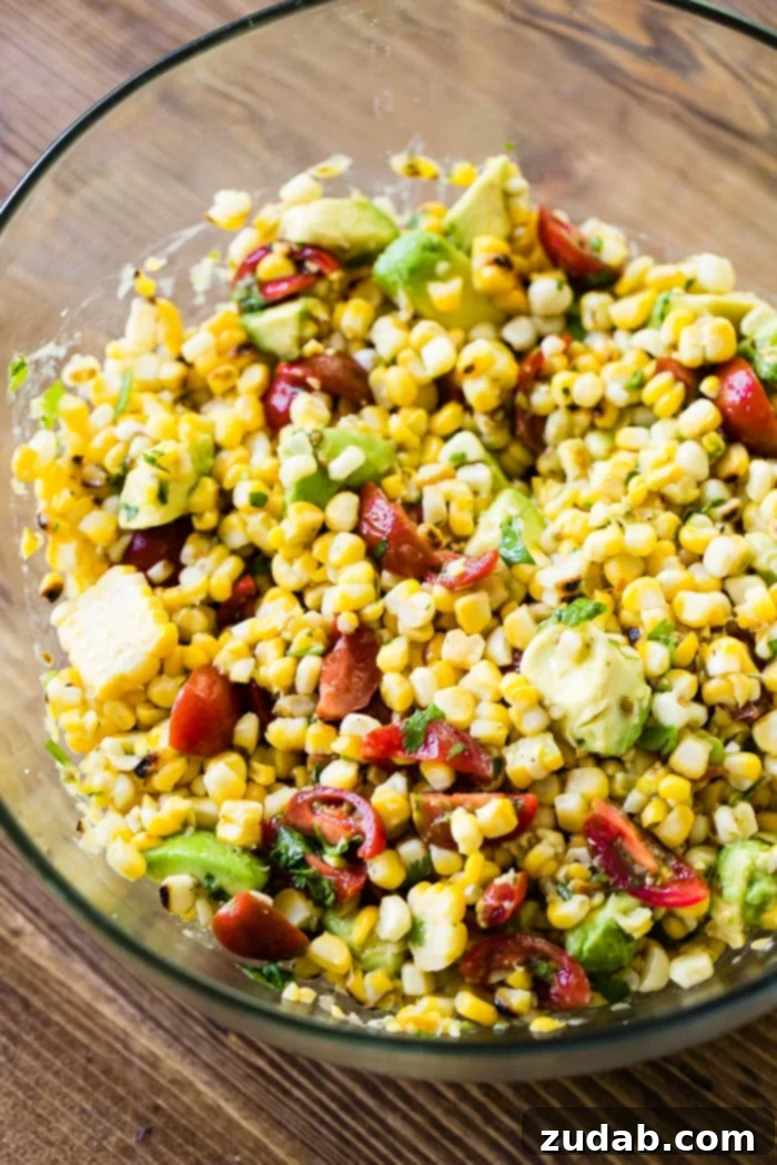 Over 25 Healthy Recipes 7 A close-up of a vibrant grilled corn, avocado, and tomato salad in a bowl, showcasing fresh ingredients and charred corn kernels.