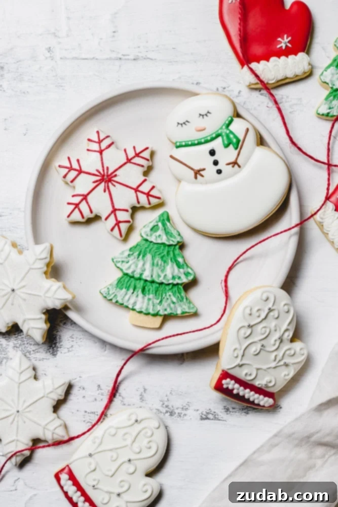 The Best Royal Icing for Holiday Cookies 4 A festive plate showcasing beautifully decorated Christmas sugar cookies with royal icing. Designs include a cheerful snowman with a green scarf, a cozy white mitten with red trim, a classic green tree adorned with white snow accents, and a radiant white star with red details. A red ribbon elegantly drapes over the plate's edge.