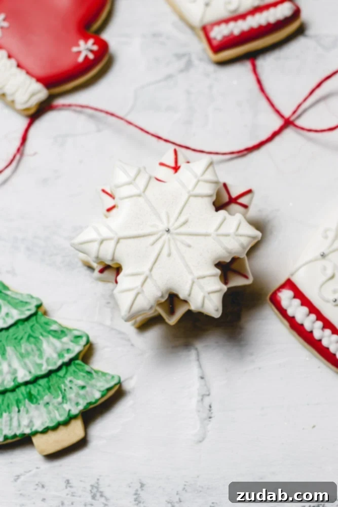 The Best Royal Icing for Holiday Cookies 6 Festive Christmas sugar cookies, featuring a pristine white snowflake with white accents and a vibrant green tree adorned with delicate white snow.