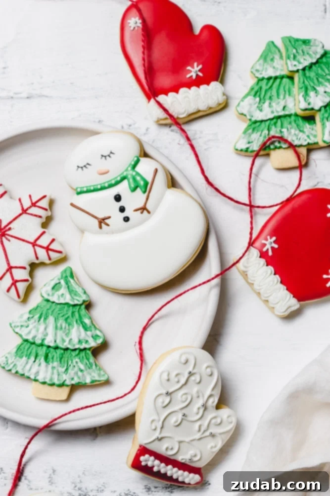 The Best Royal Icing for Holiday Cookies 7 A festive assortment of Christmas sugar cookies beautifully decorated with royal icing. Featuring a cheerful snowman with a green scarf, a cozy red mitten, a delicate snowflake with red accents, and a classic green tree adorned with white snow.