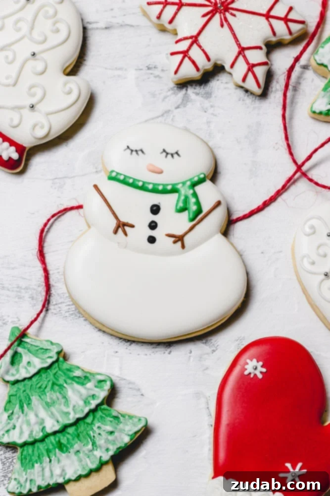 The Best Royal Icing for Holiday Cookies 9 A delightful collection of Christmas sugar cookies adorned with royal icing. The plate features a cheerful snowman wearing a green scarf, a vibrant green tree dusted with white snow, a cozy red mitten, and an elegant white mitten.
