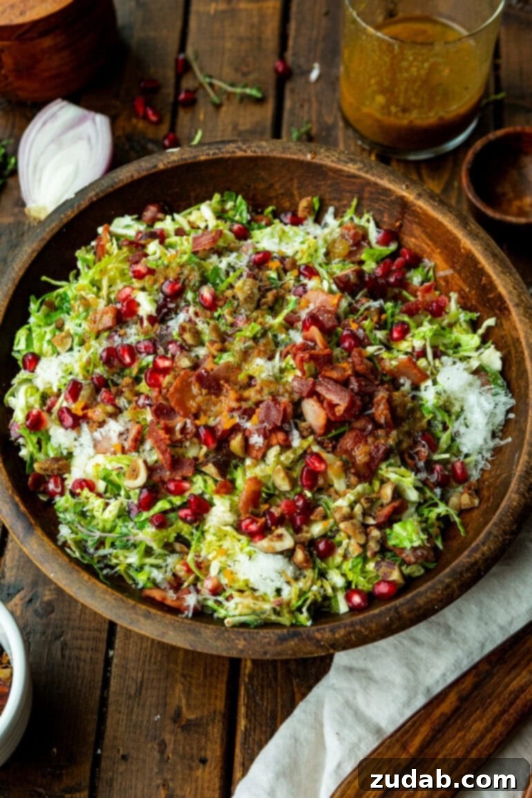 Jeweled Pomegranate Brussels Sprout Salad 5 A vibrant bowl of pomegranate Brussels sprout salad, showcasing the delightful blend of crisp Brussels sprouts, smoky bacon bits, glistening pomegranate seeds, and crunchy candied nuts.