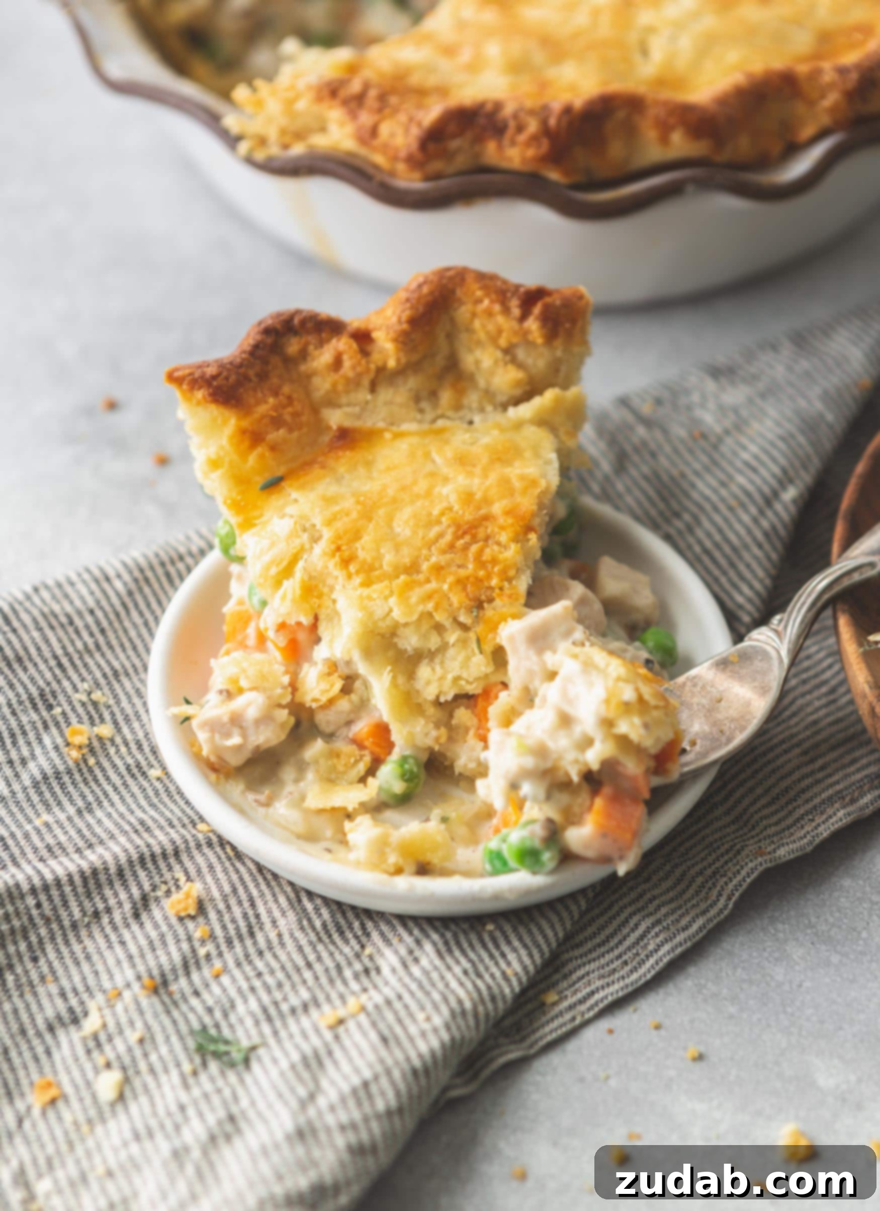 Turkey Pot Pie A slice of turkey pot pie on a small plate. The crust is golden brown and the filling is creamy and contains carrots and pies.