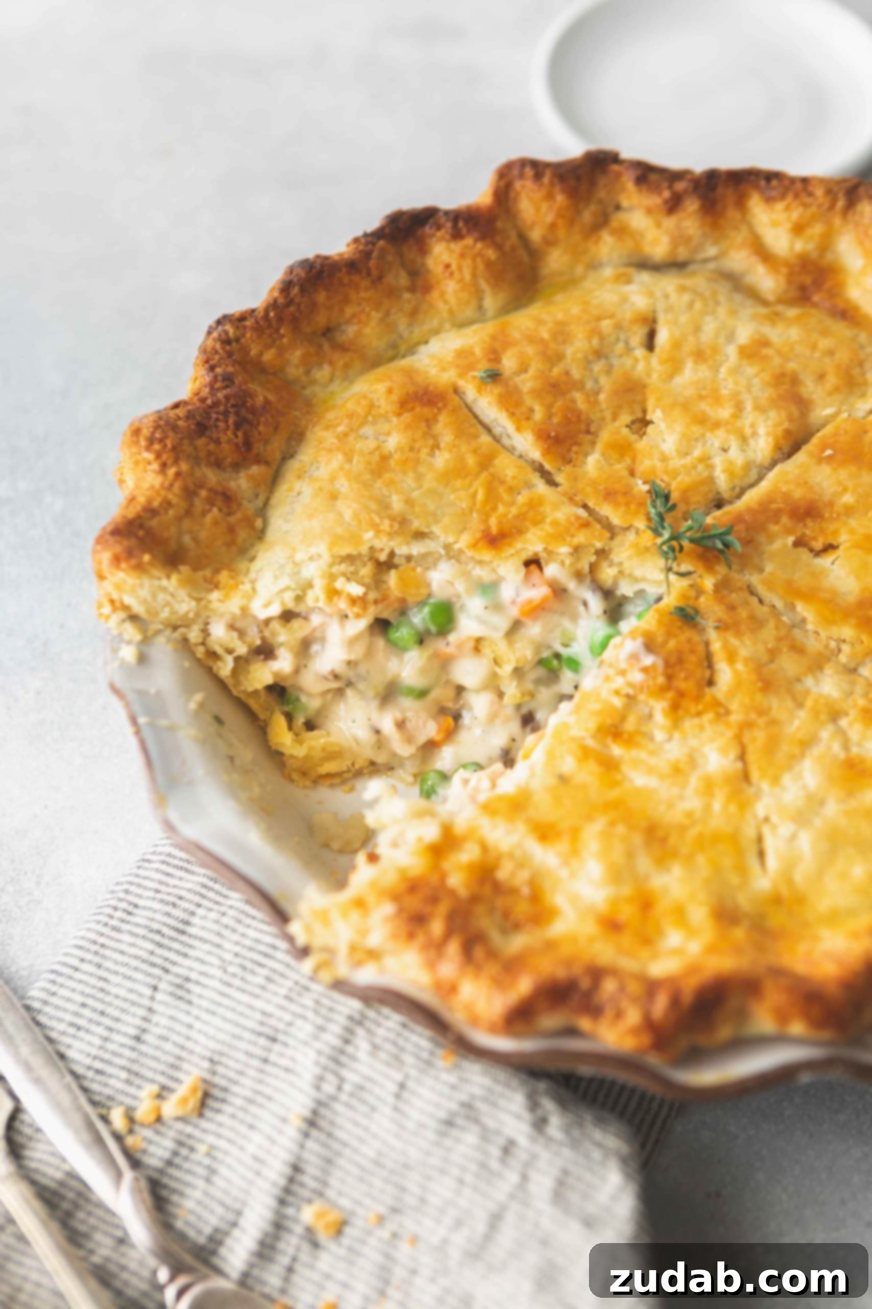 Turkey Pot Pie A baked turkey pot pie that has a slice removed showing the creamy filling with turkey, peas and carrots.