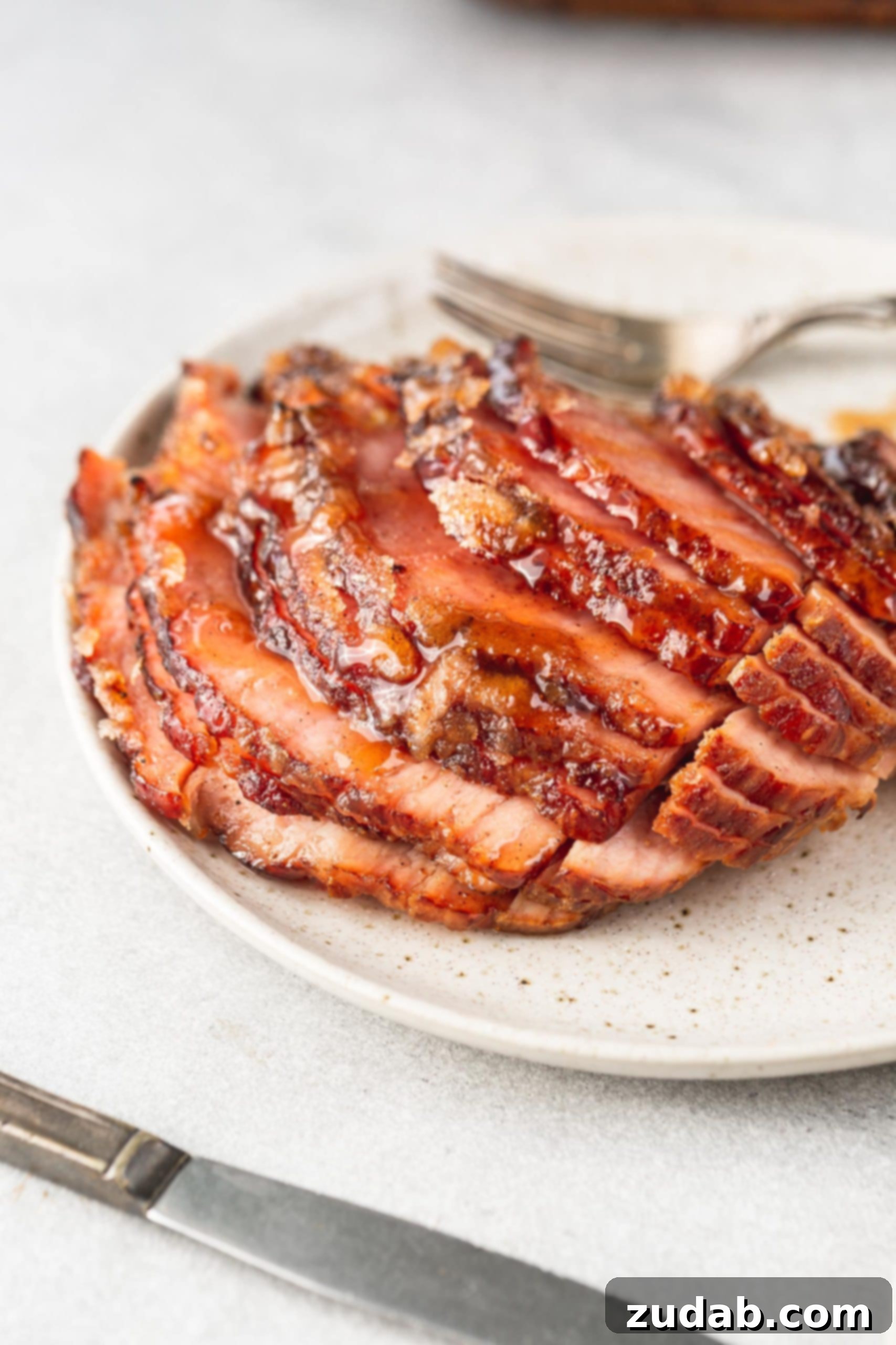 A close-up shot of a spiral-cut honey glazed ham, with slices slightly separated, highlighting the juicy texture and the irresistible, sticky honey glaze.
